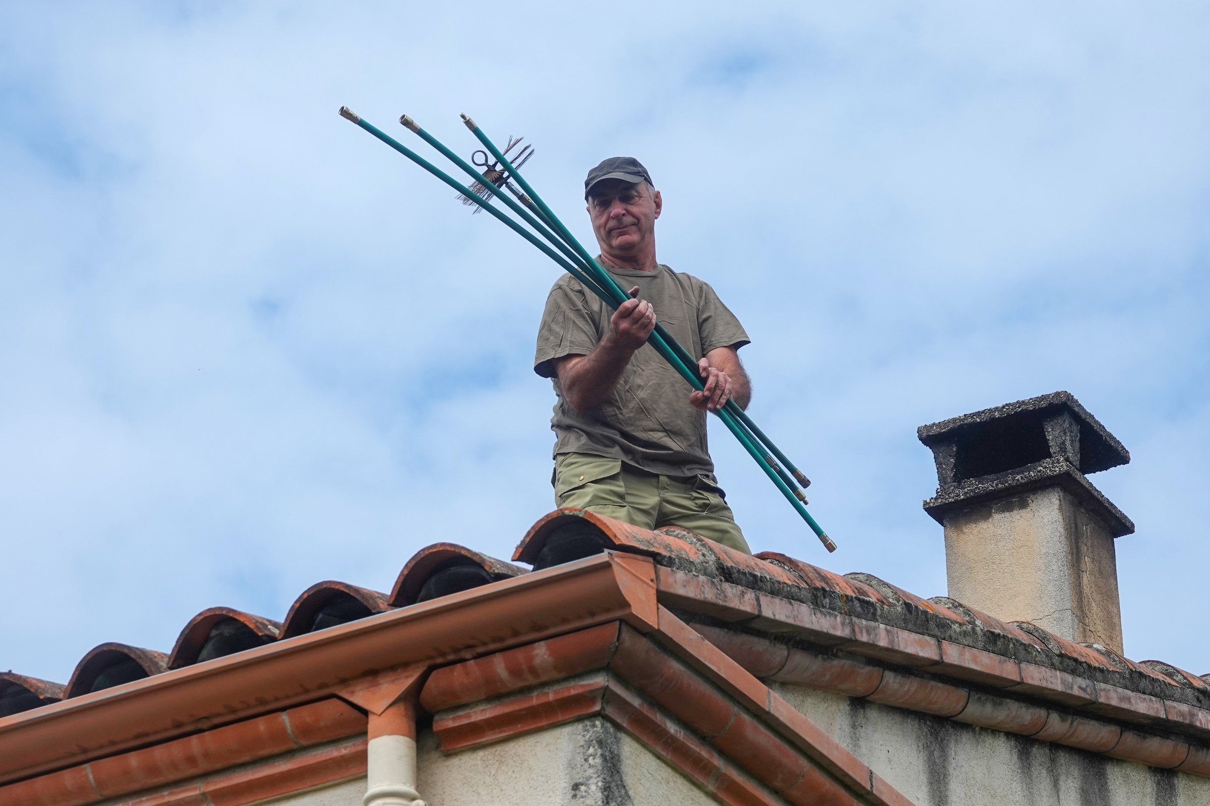 Man preparing brushes to clean the chimney on the roof