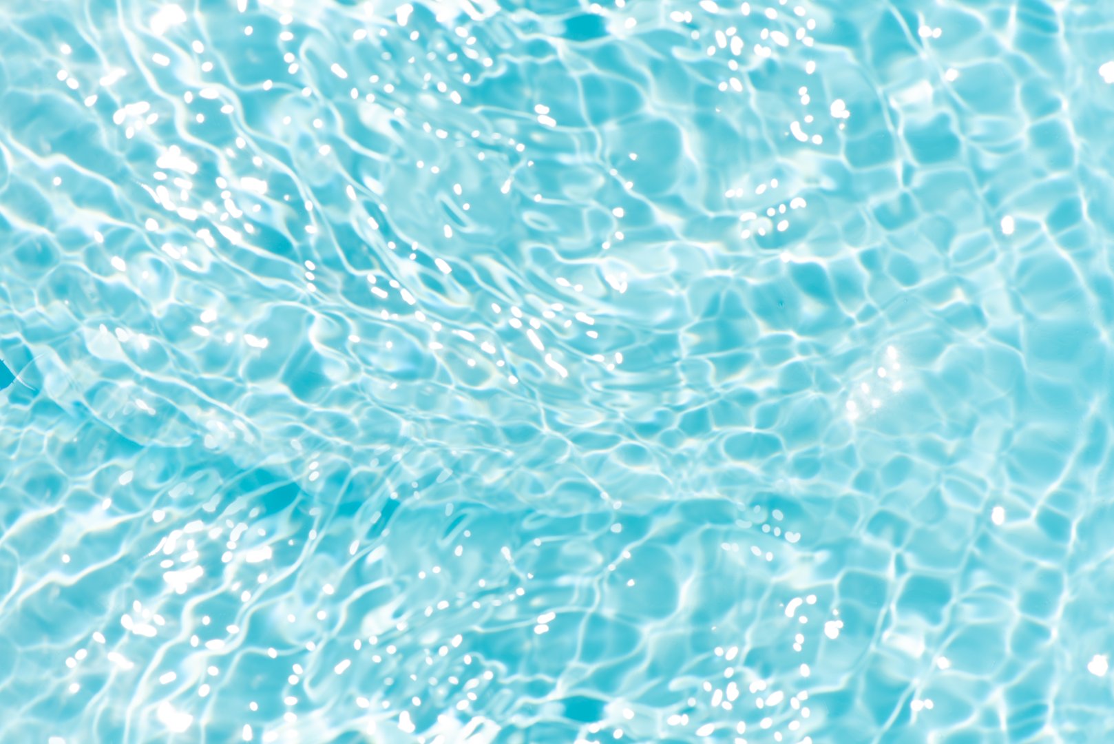 Blue water with ripples on the surface. Defocus blurred transparent blue colored clear calm water surface texture with splashes and bubbles. Water waves with shining pattern texture background.