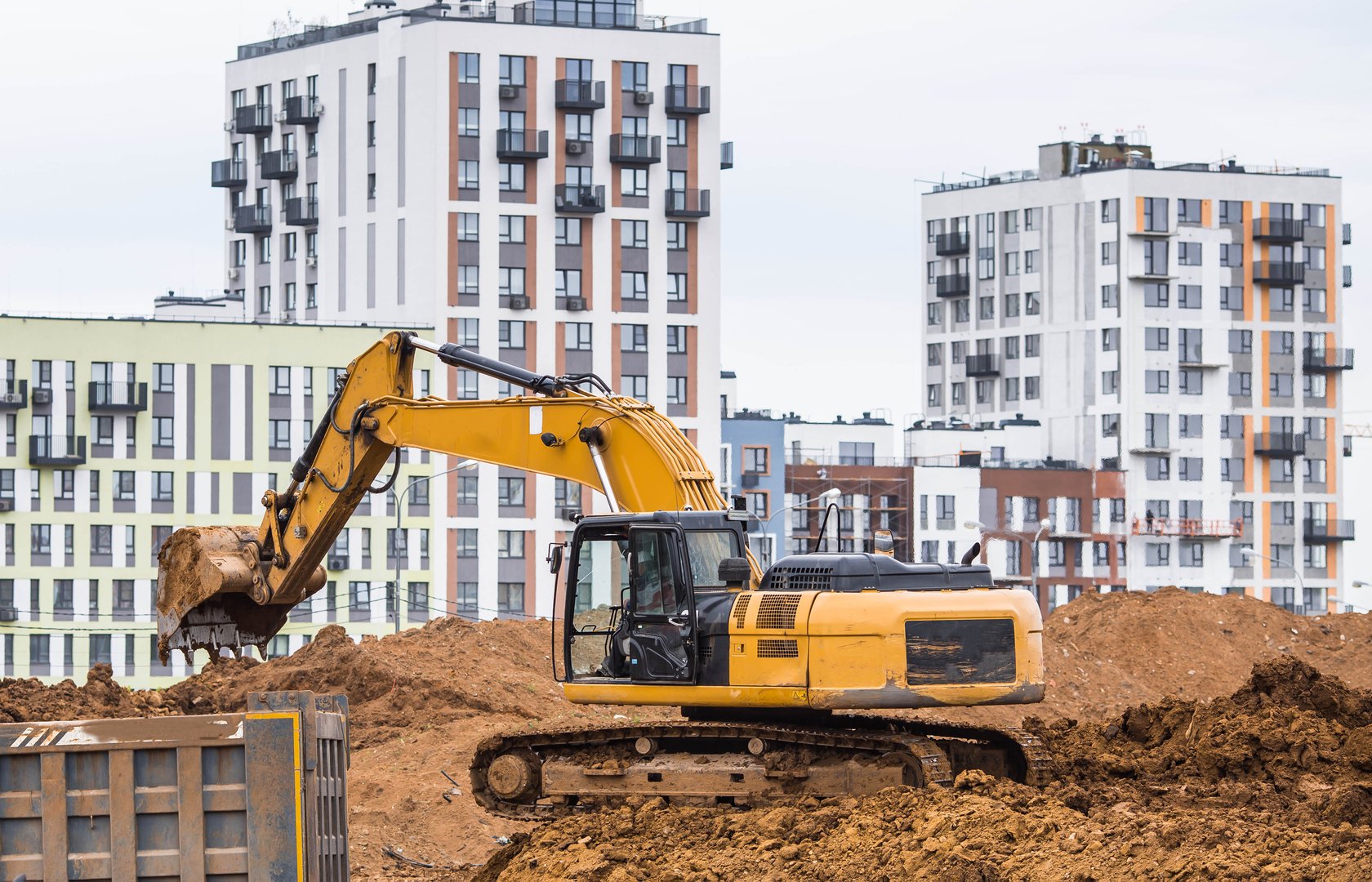 An excavator on a construction site in close-up. An excavator digs the ground with a bucket for construction. Heavy machinery for construction and landscaping.