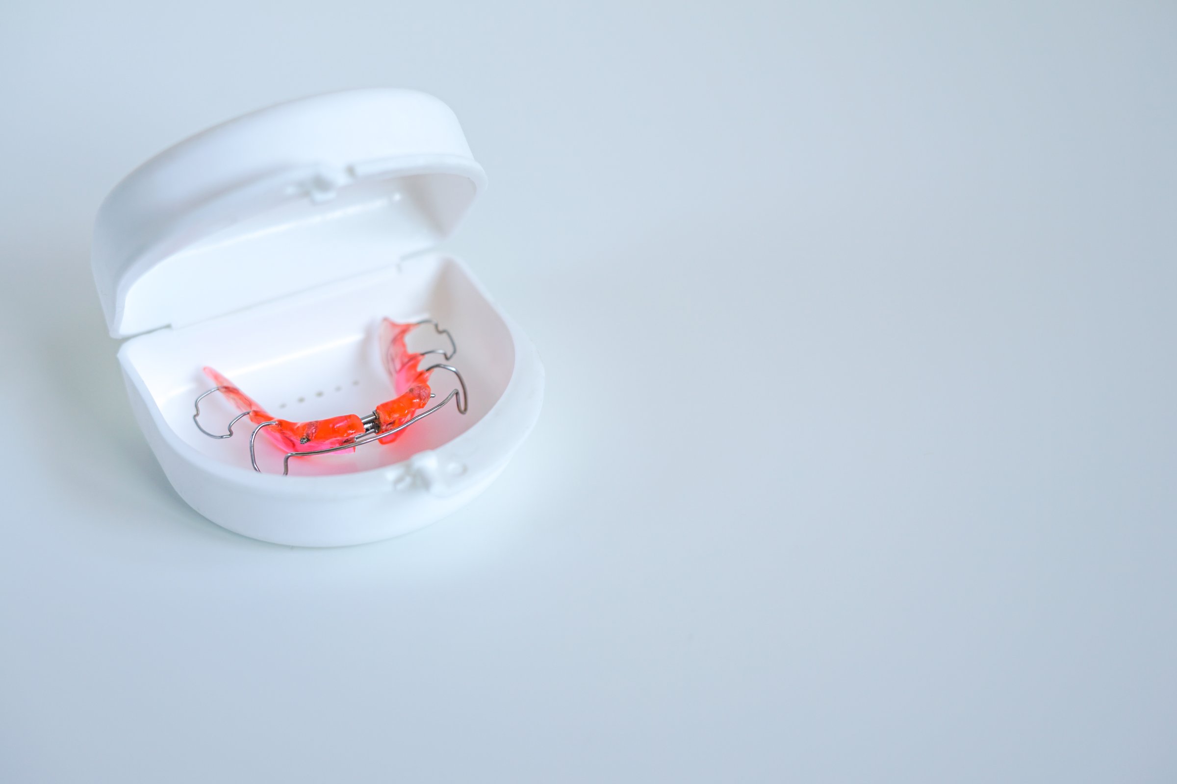 An orthodontic palatal expander in a white protective case, used for jaw or palate expansion treatment