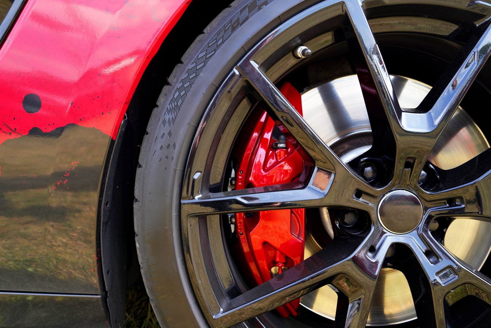Alloy wheel with calipers and racing brakes of the sport car. Racing brake disc and low profile tyres. Race car test driving. Lower-profile tires of drag and drift cars. High-performance sports cars.