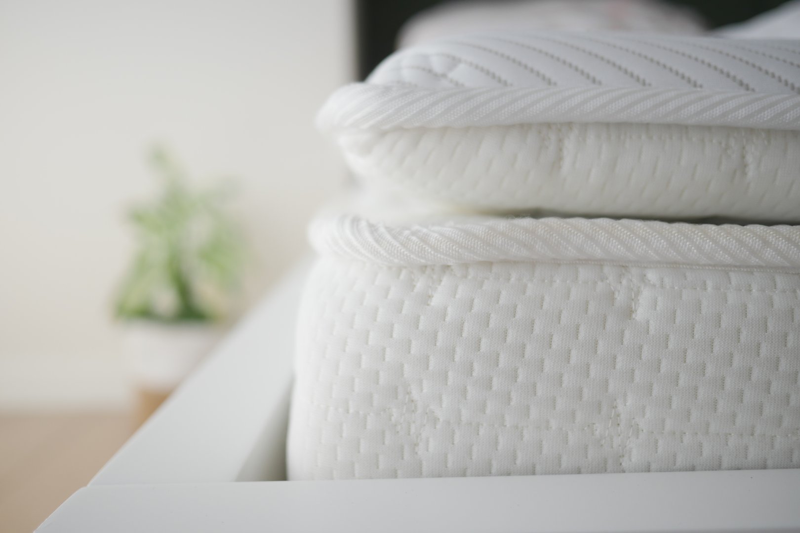 Soft white mattresses are neatly arranged on a contemporary bed frame.