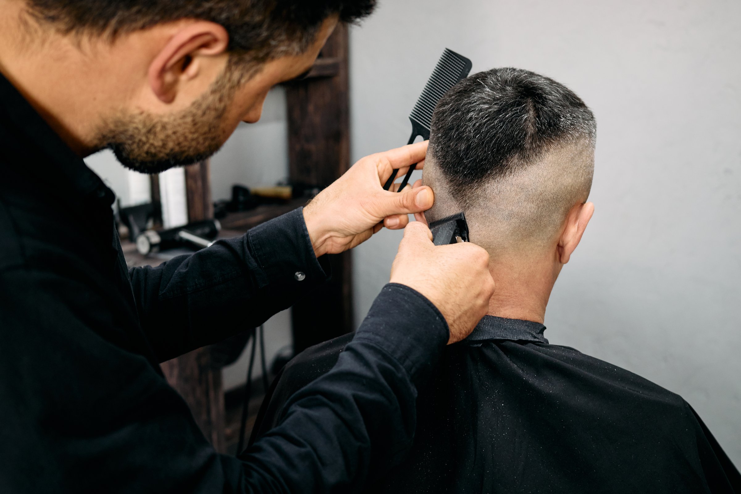 A barber skillfully trims a client's hair in a contemporary barbershop. The atmosphere is relaxed as the stylist focuses on creating a clean look with precise techniques.