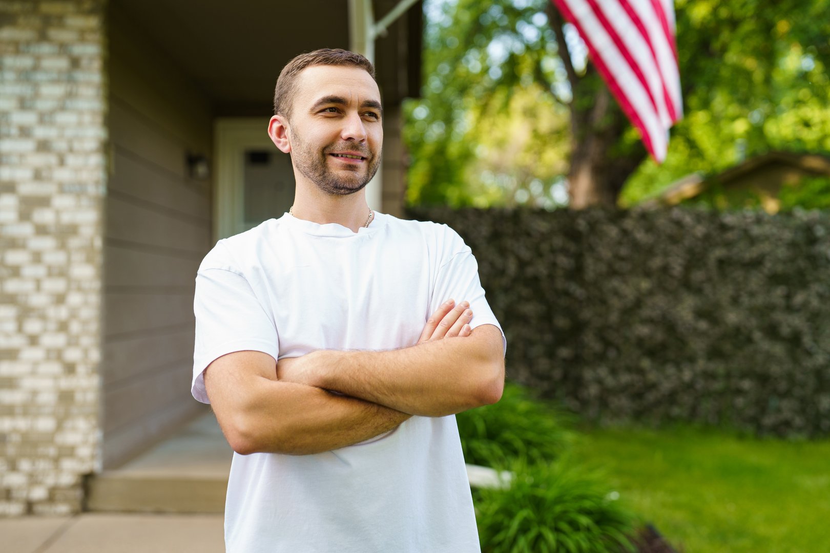 Handsome young man with crossed hands in front of his american house.