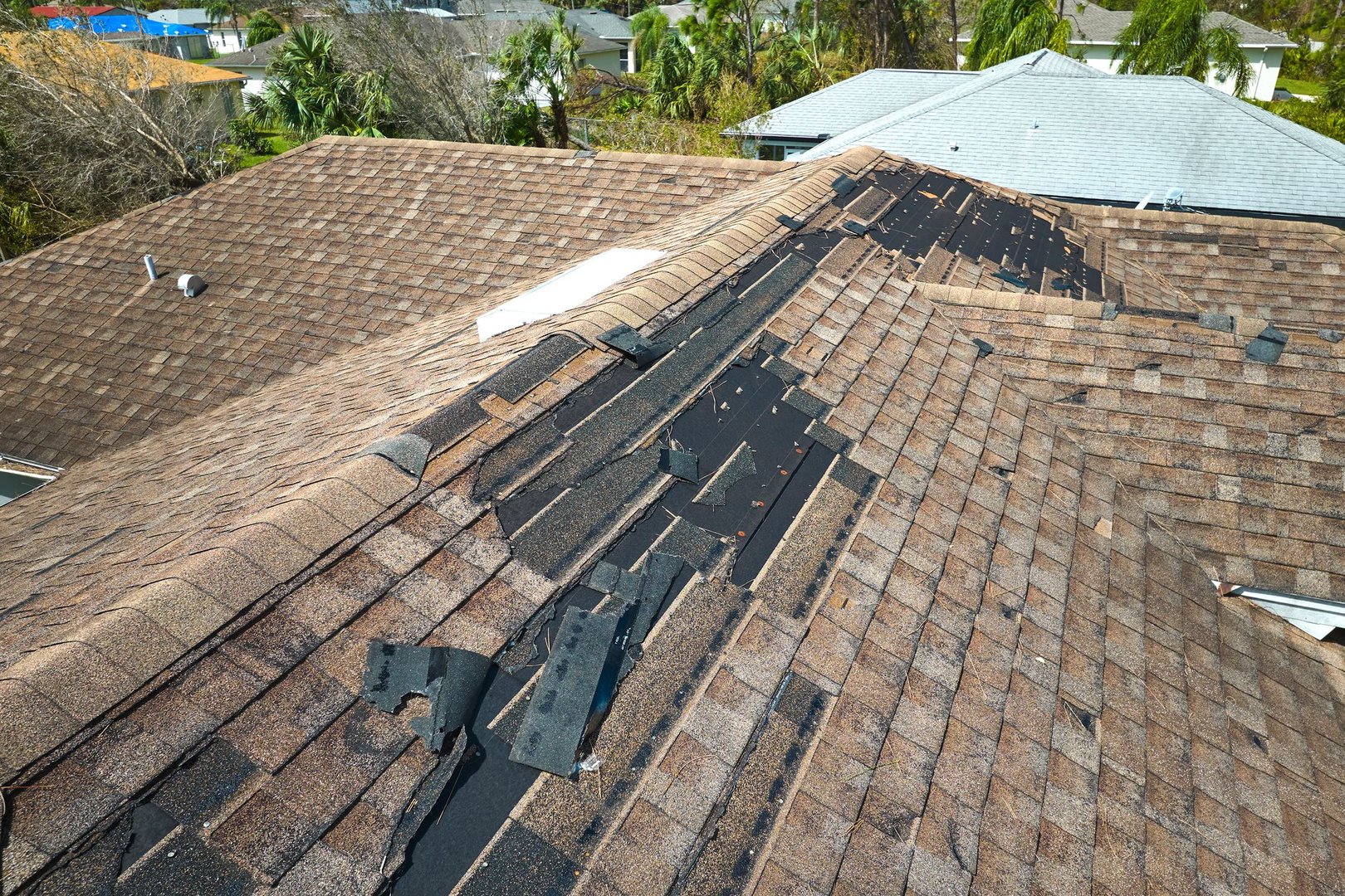 Damaged house roof with missing shingles after hurricane Ian in Florida. Consequences of natural disaster.