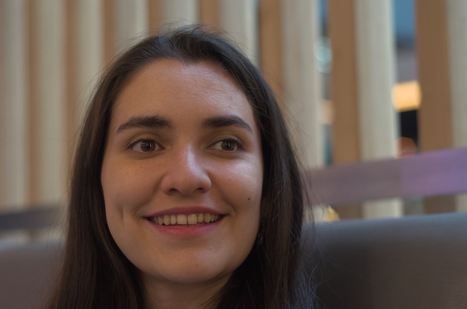 Portrait of a cheerful young hispanic woman smiling and enjoying her time in a modern cafe, radiating happiness and relaxation