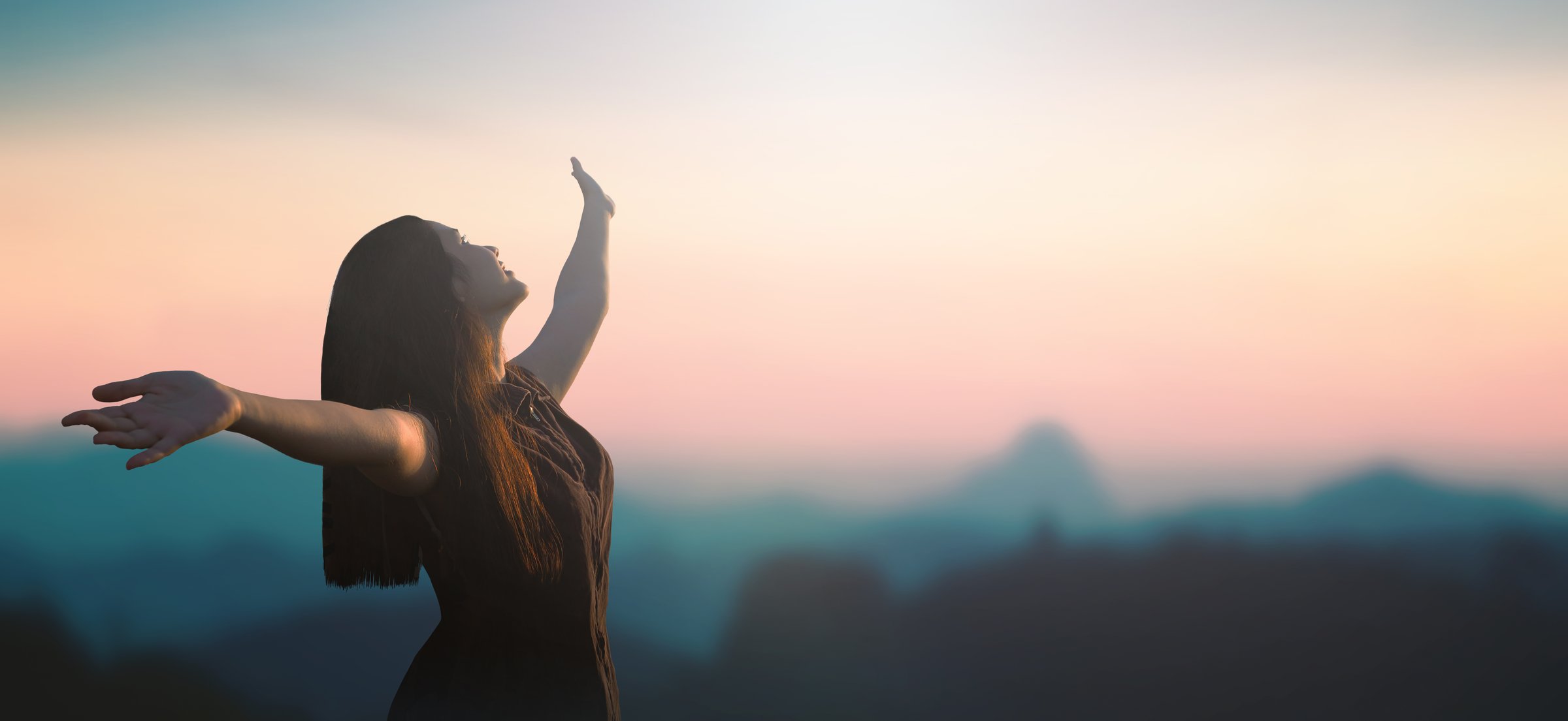 Healthy woman raised hands for praise and worship God at mountain sunrise background