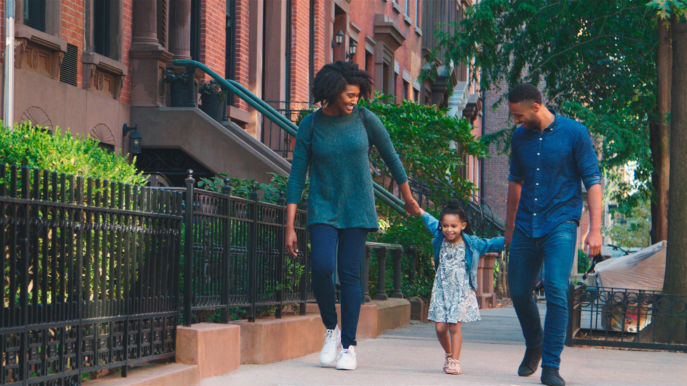 Family Shot With Parents Holding Hands With Daughter As They Walk Along Street In New York City