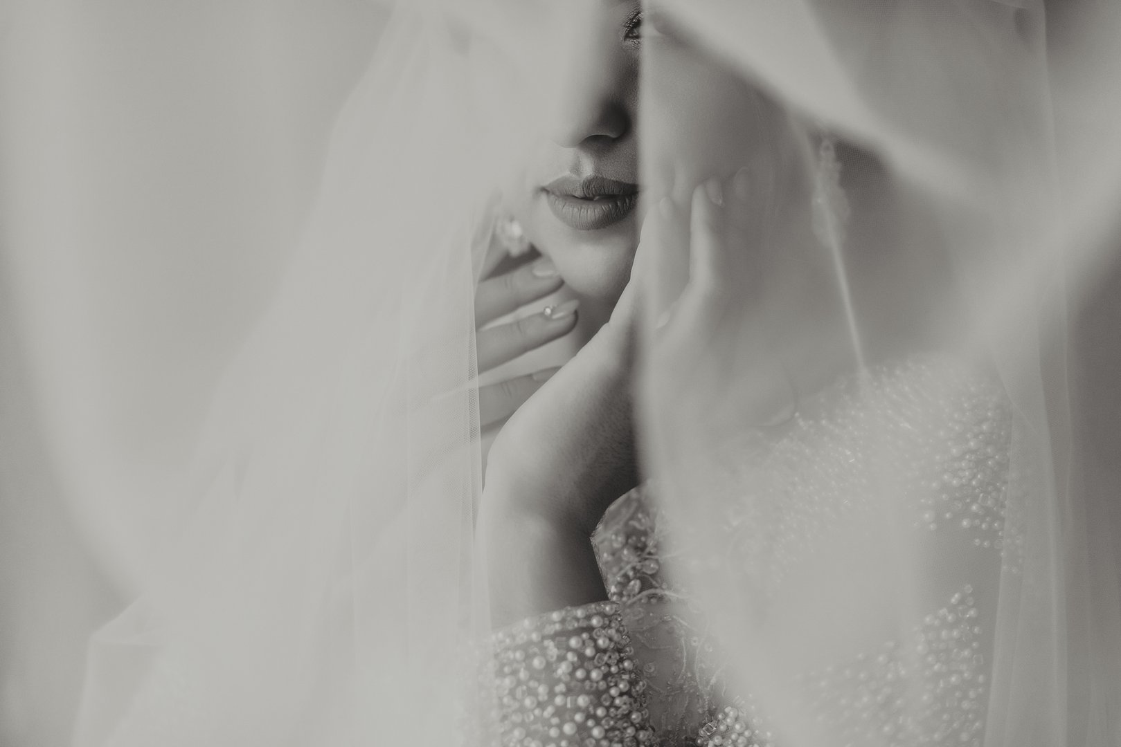 Female beauty. Cute woman at home. The bride poses under a veil. A stylish woman wears a white dress. Professional make-up and hair. On the bride's head is a crown and a long veil.