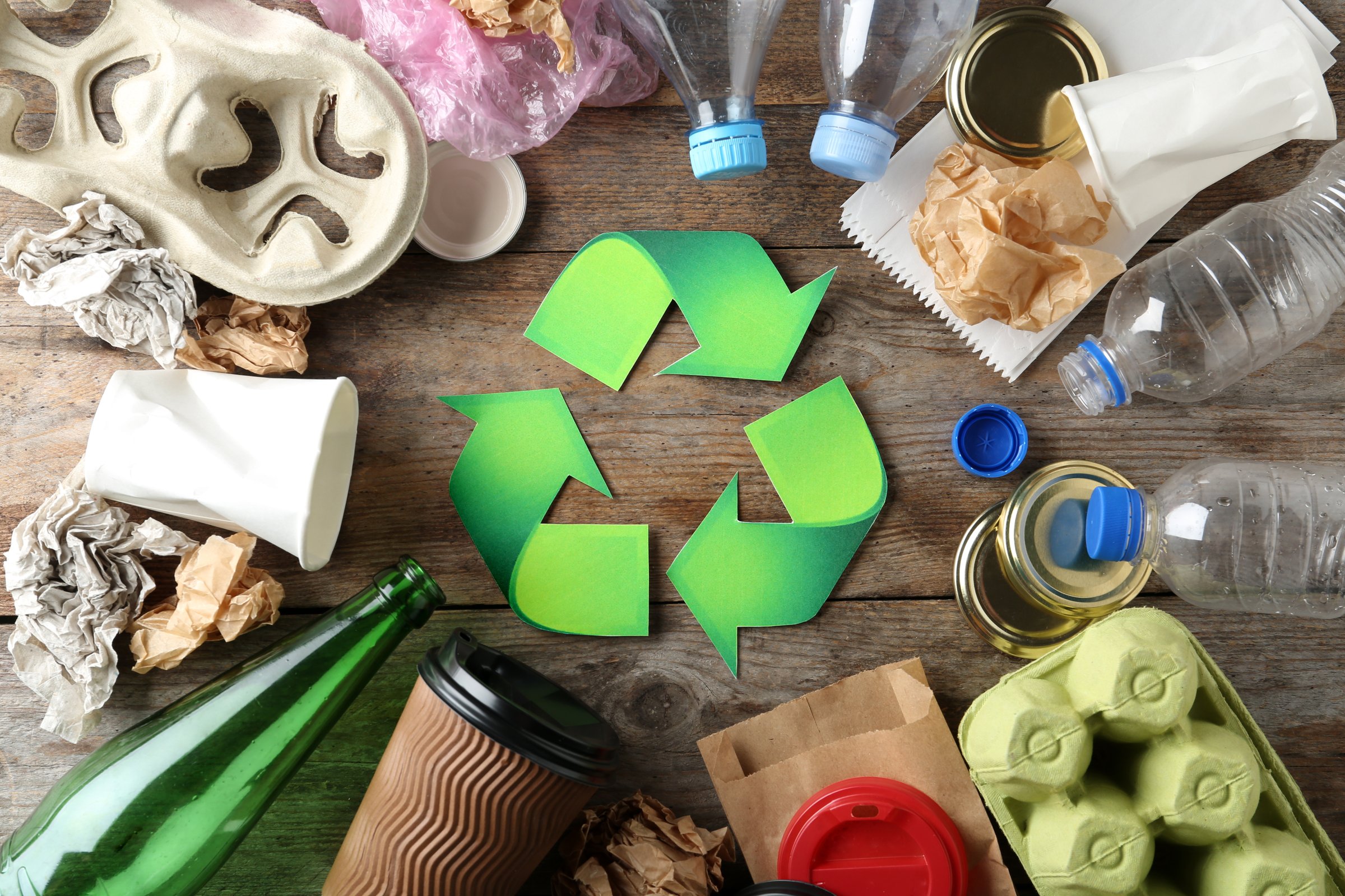 Recycle Symbol with Various Recyclable Waste on Wood Background.