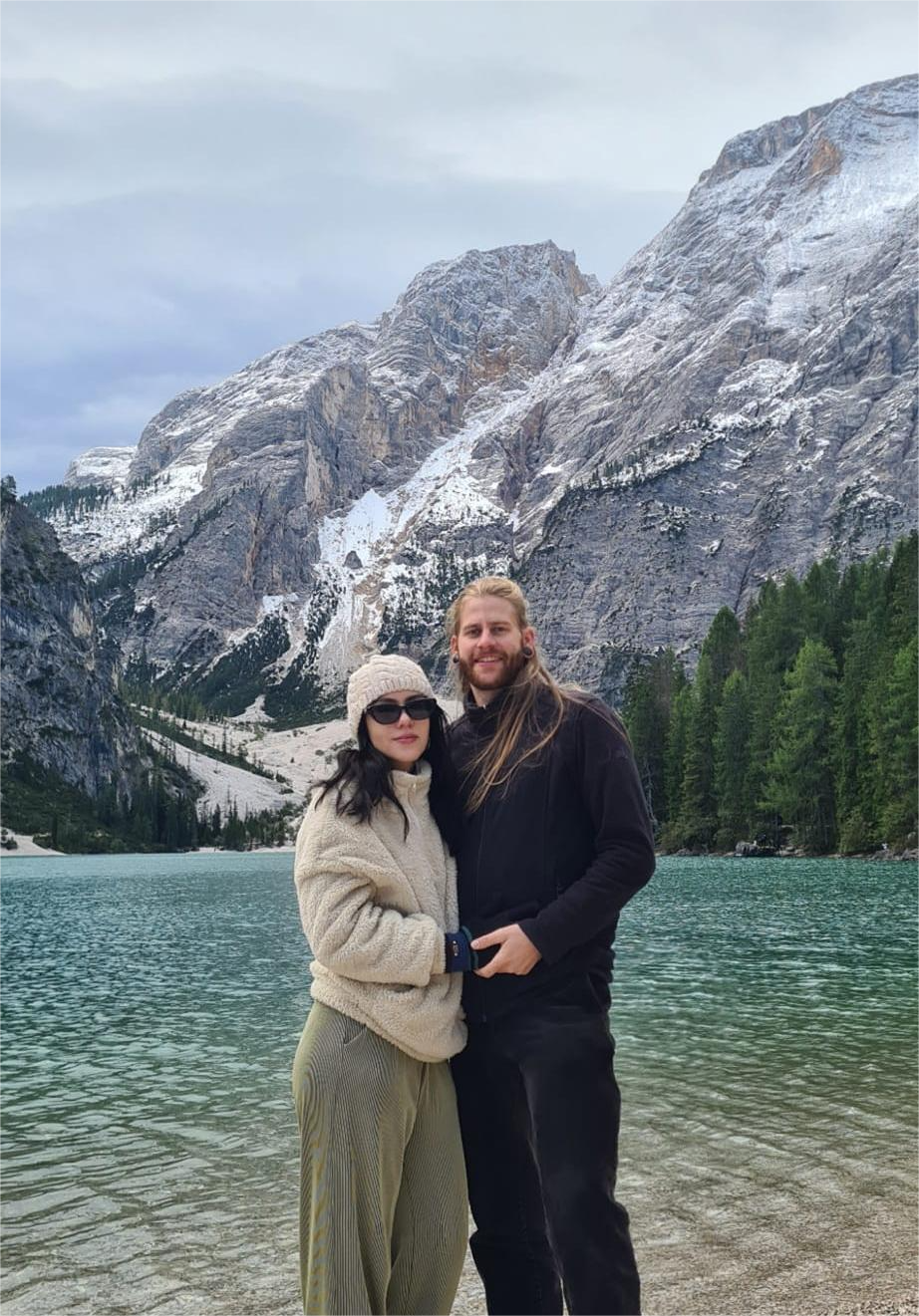 Person in a black jacket and jeans standing in front of the Leaning Tower of Pisa on a clear day.