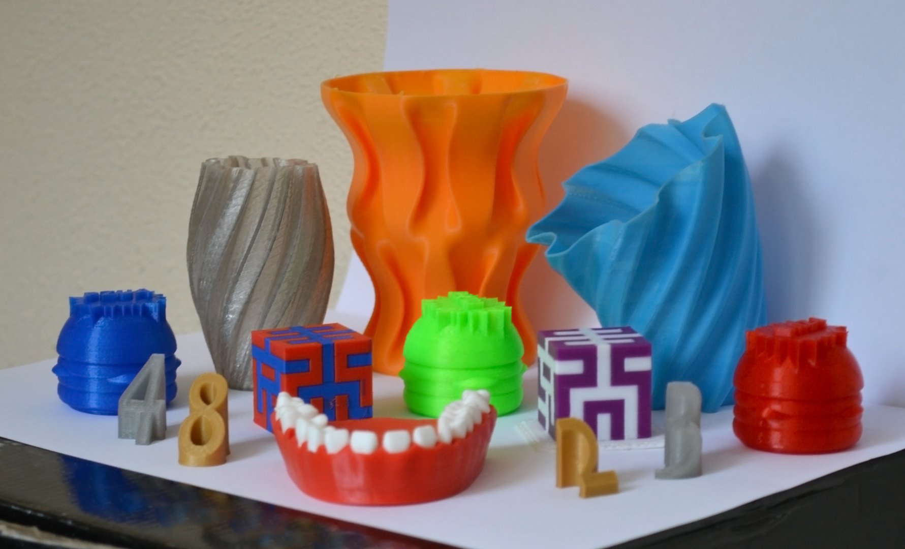 Models printed by 3d printer. Bright colorful objects printed on 3d printer on table.Automatic three dimensional printer performs plastic modeling in laboratory. Progressive modern additive technology