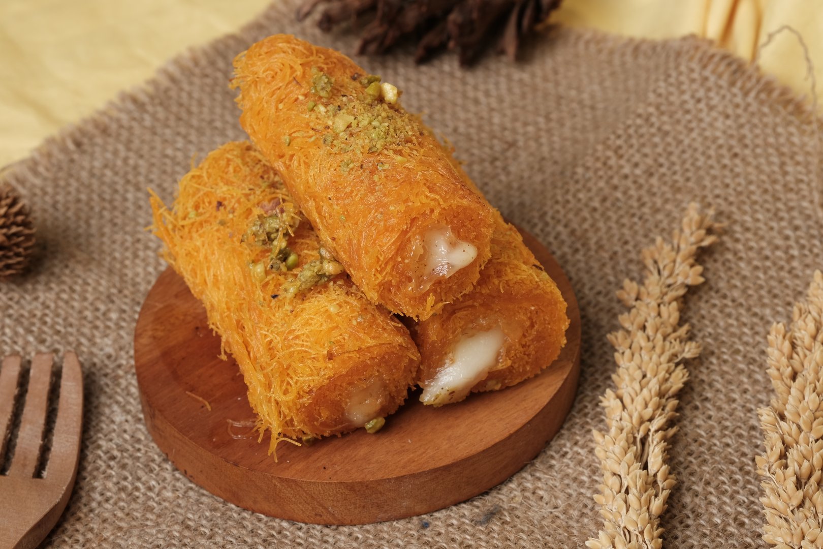 Traditional Middle Eastern kunafa rolls made with shredded phyllo dough, filled with cream, and garnished with crushed pistachios on top