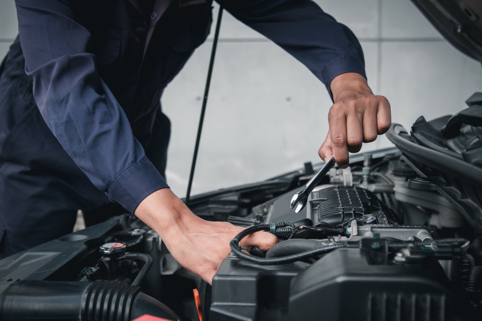 Mechanic using wrench while working on car engine outside the service center , Repair and service.