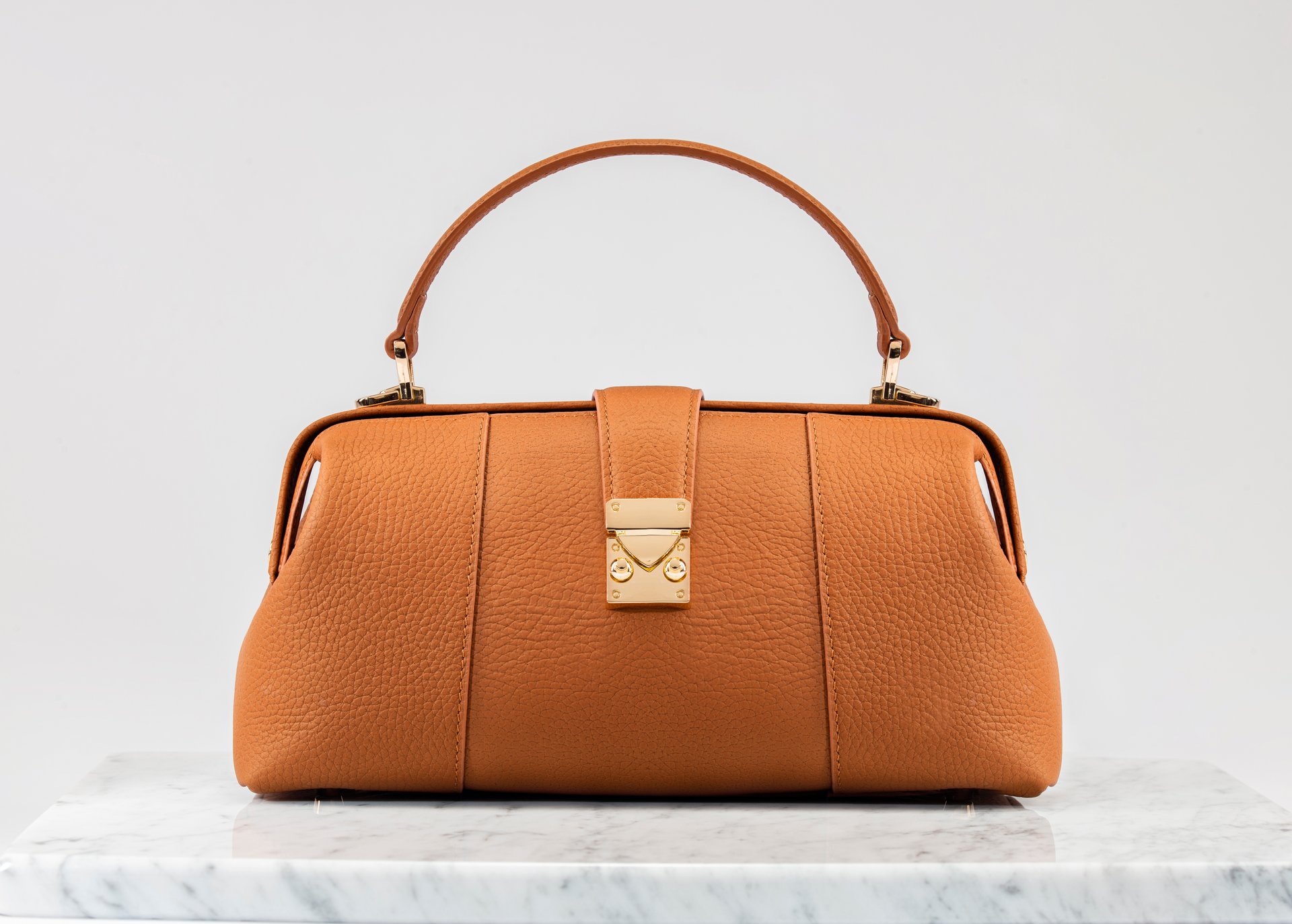 Women 's bag. Luxury, orange leather handbag on white background, on marble floor. A elegant bag is see from front side. Fashionable trendy.