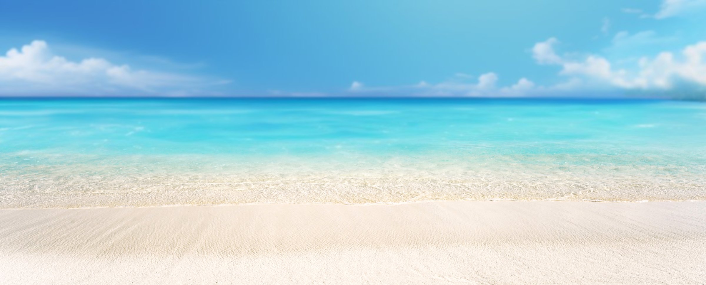 Natural panorama of a beautiful beach with white sand, calm rolling clear turquoise water and blue sky with clouds on a hot sunny day.