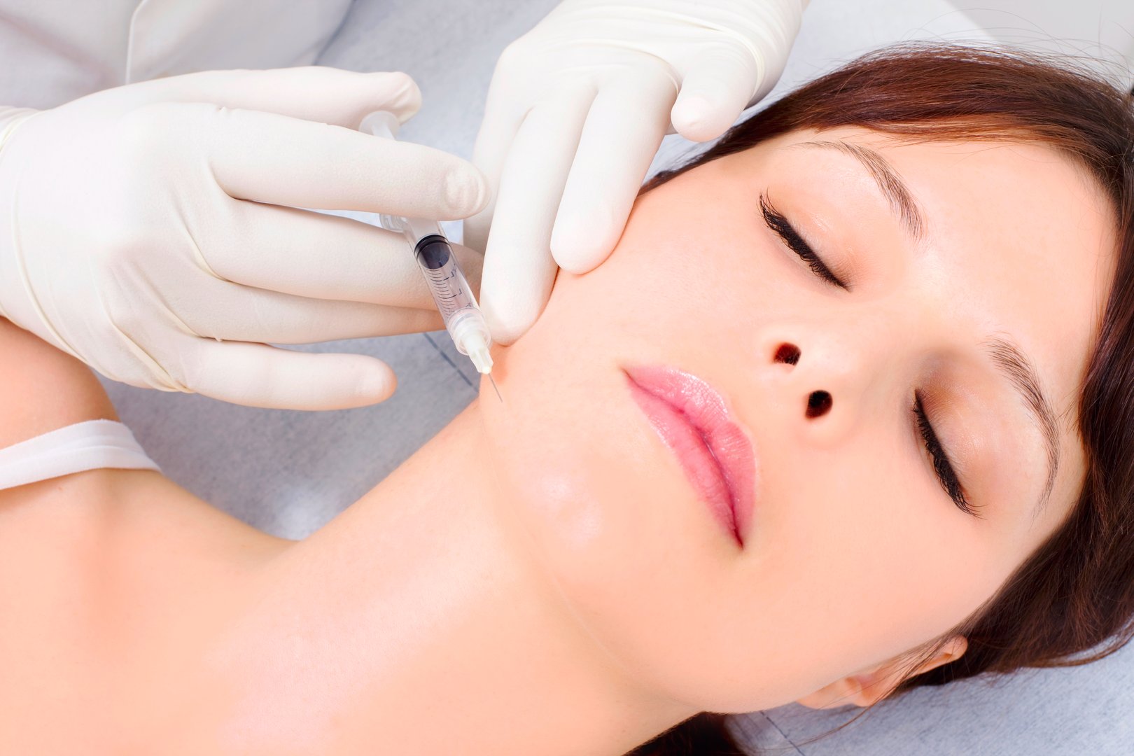 young caucasian woman receiving an injection of botox from a doctor  isolated on white background