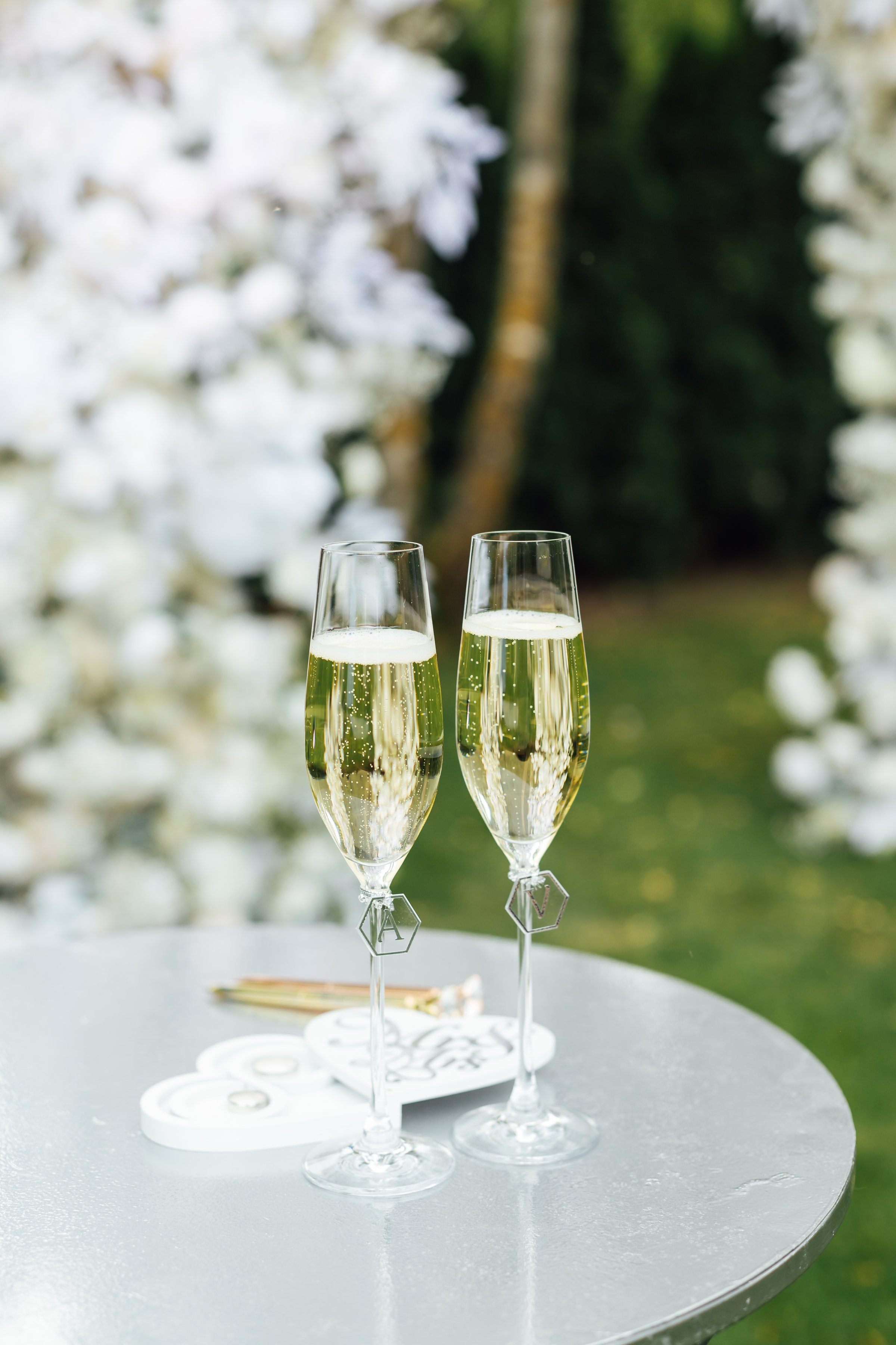 Elegant glasses of champagne for the newlyweds stand on the table next to the ceremony arch.