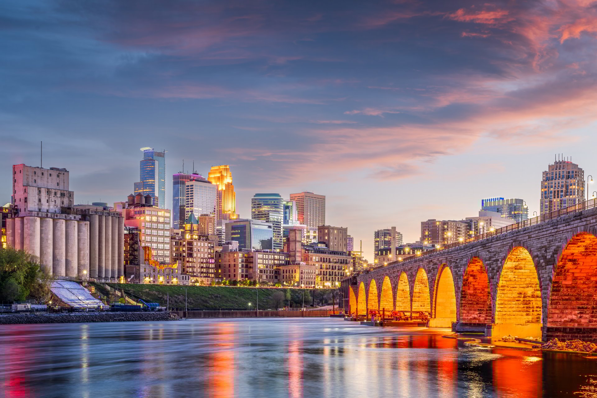 Minneapolis, Minnesota, USA skyline with the Stone Arch Bridge on the Mississippi River at dusk.
