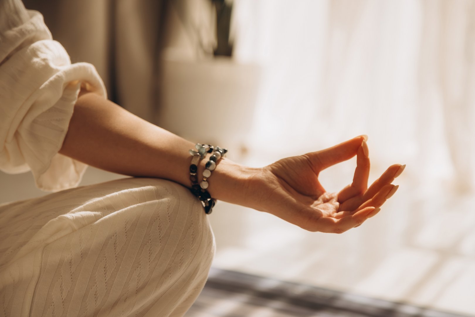 Closeup of woman hand in yoga symbolic gesture mudra wearing bracelets