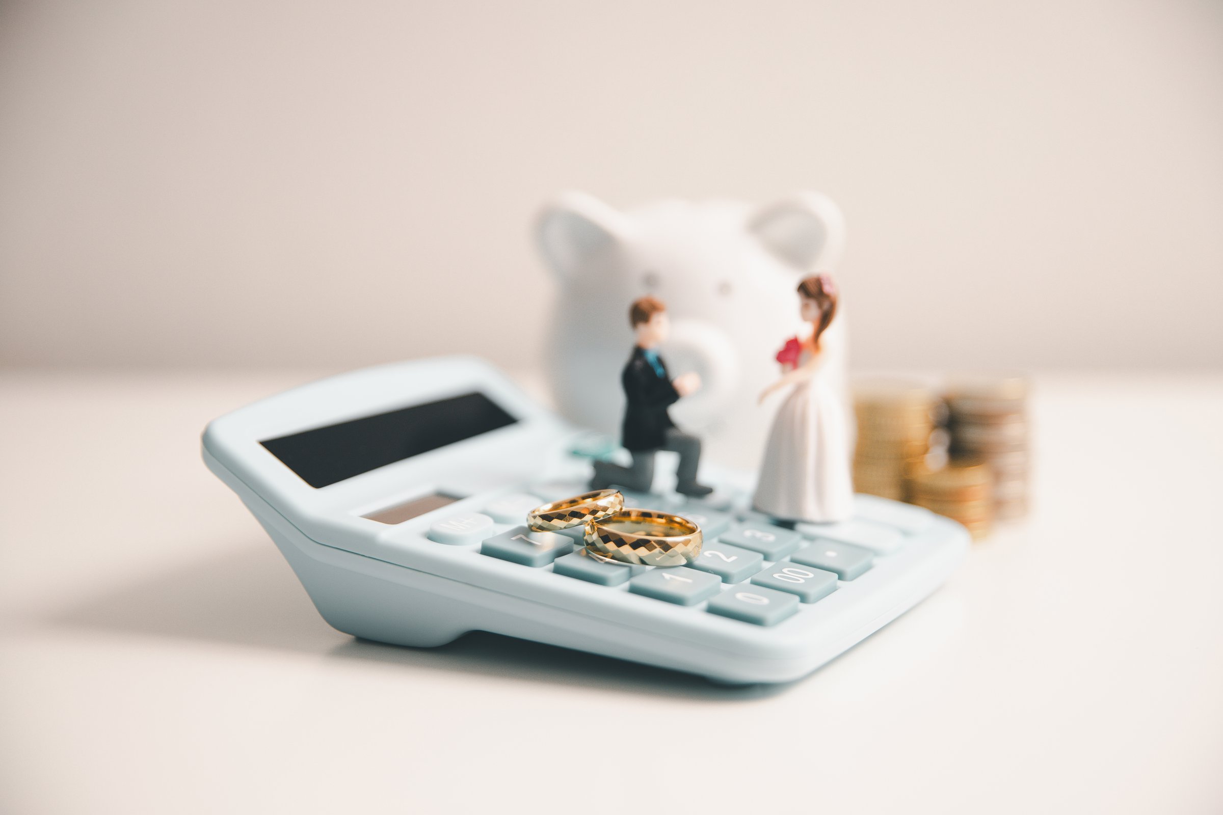 Save money for wedding and planning wedding concept. Sustainable financial goal for family life or married life. Miniature wedding on rows of rising coins, depicts savings or growth for new family.