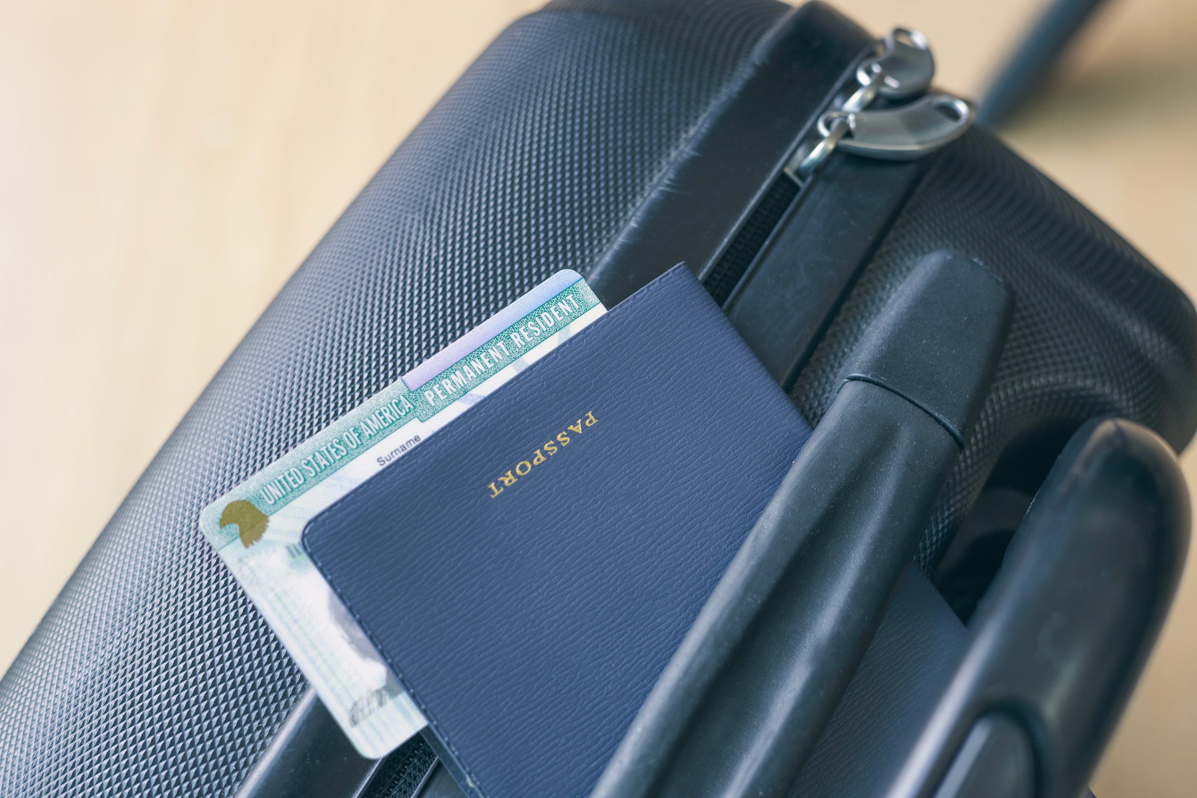 United States passport and permanent resident (green) card on suitcase. Application to register permanent residence.