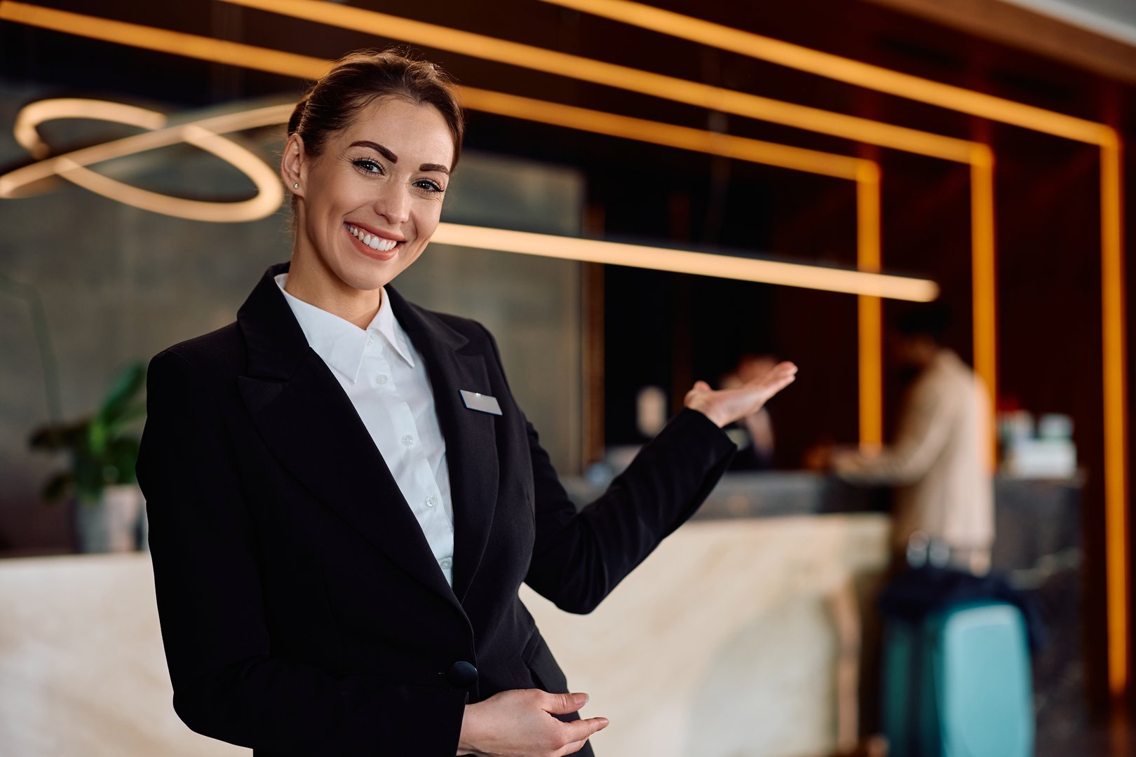Happy concierge welcoming guests in a hotel and looking at camera.