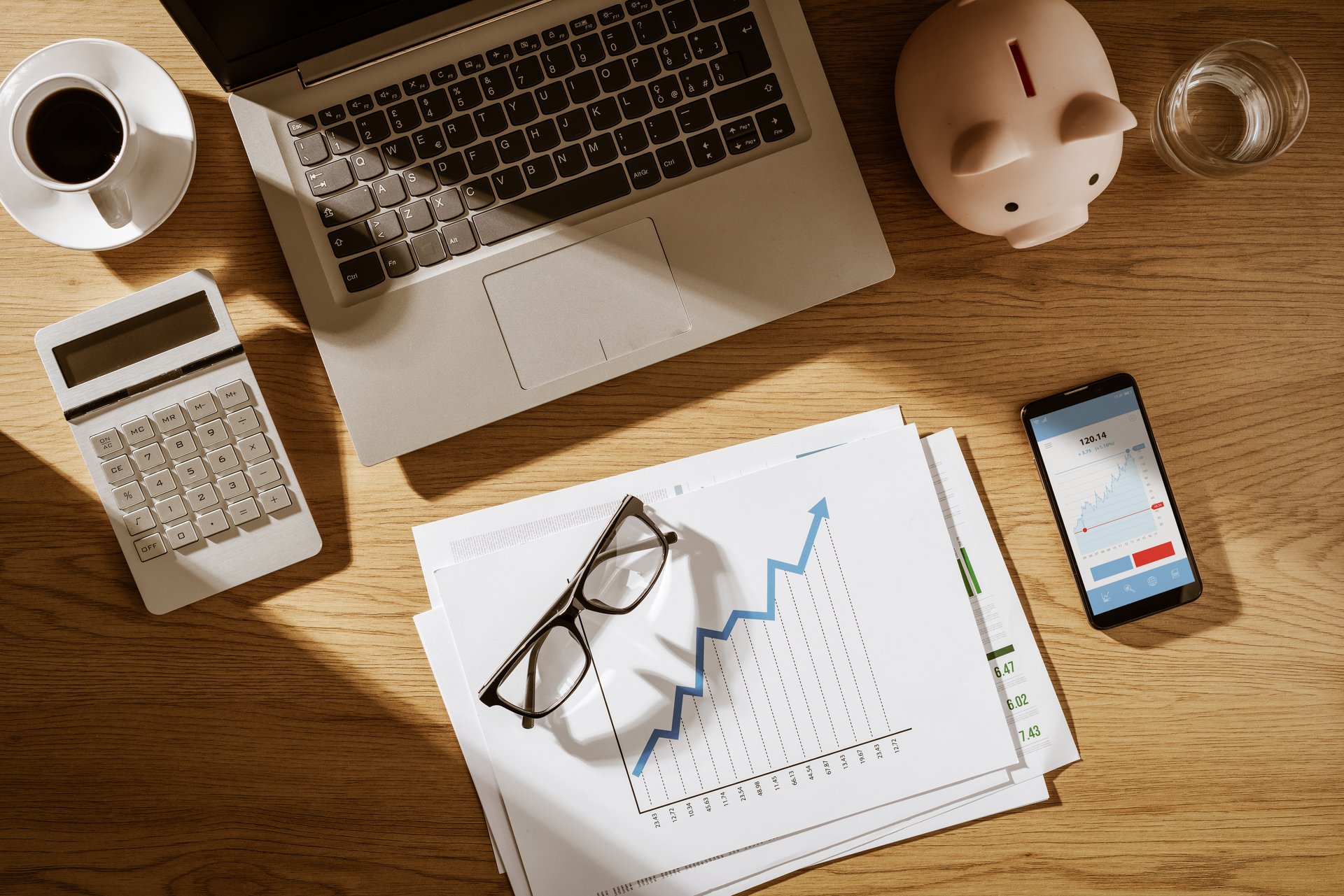 Corporate business desktop with printed financial charts and digital chart on a mobile app