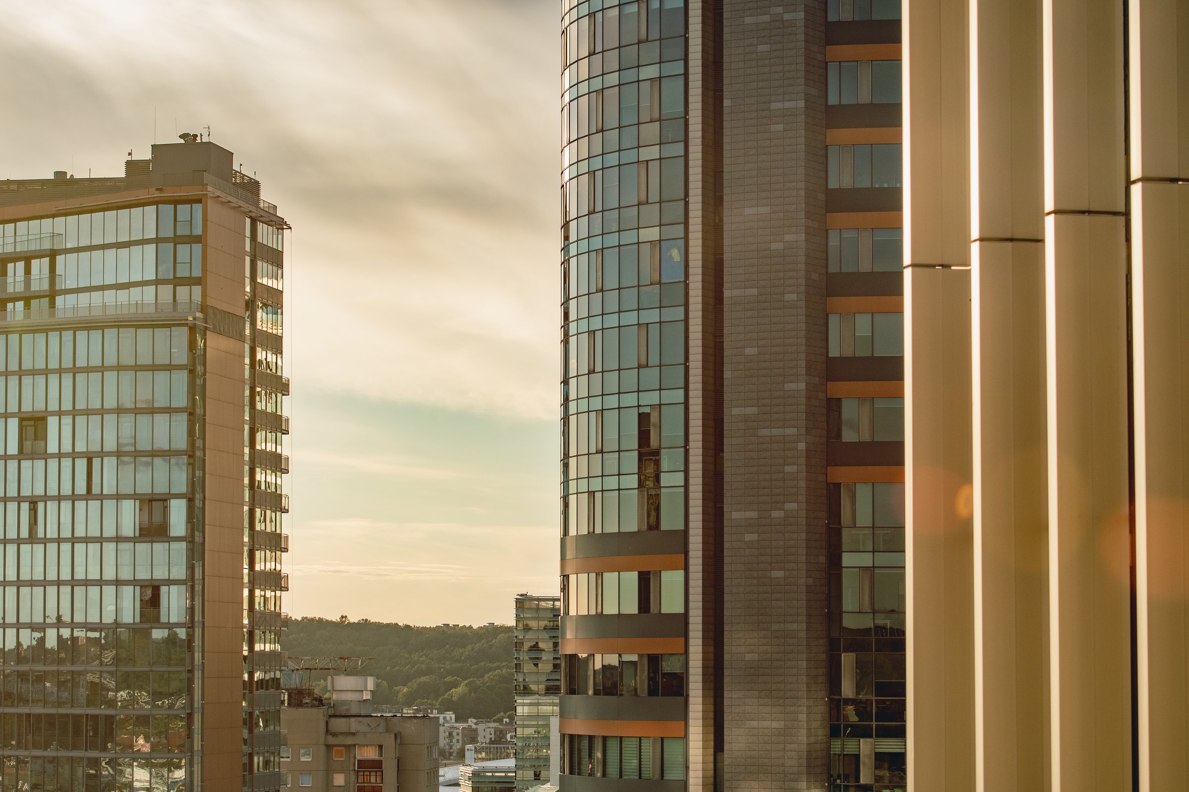Modern business district at sunset featuring new high-rise glass office buildings and a city skyline in Vilnius, symbolizing corporate growth, urban development