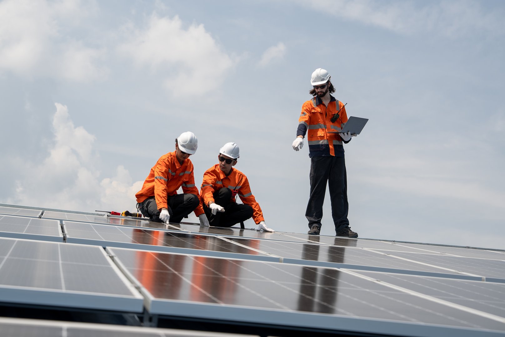 Engineer team checking solar cell or photovoltaic cell installed on the roof of the factory. Technician worker repair or inspect the system. Industrial renewable energy concept