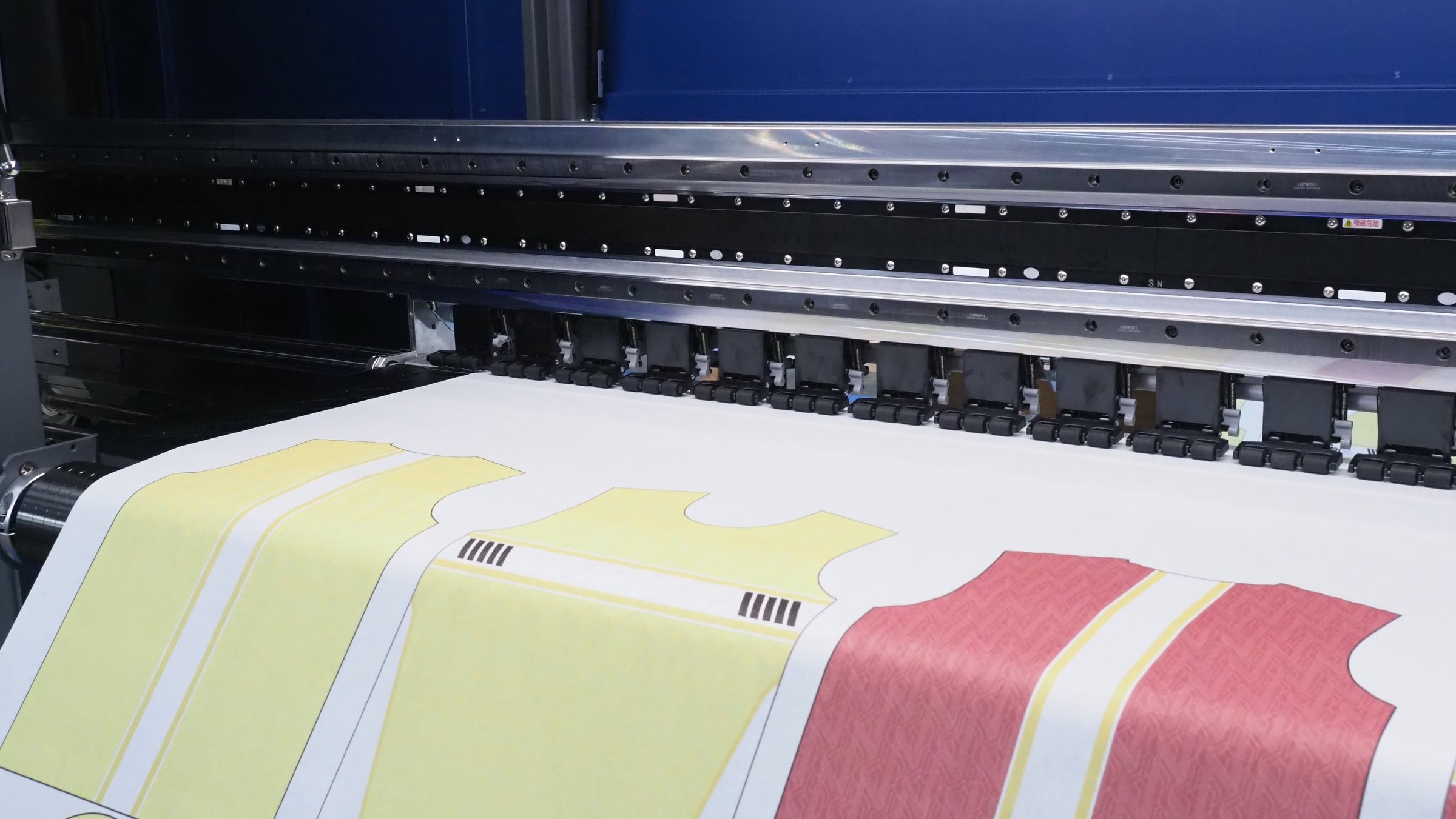 a digital textile printer in printing colorful shirt patterns directly onto fabric rolls.
