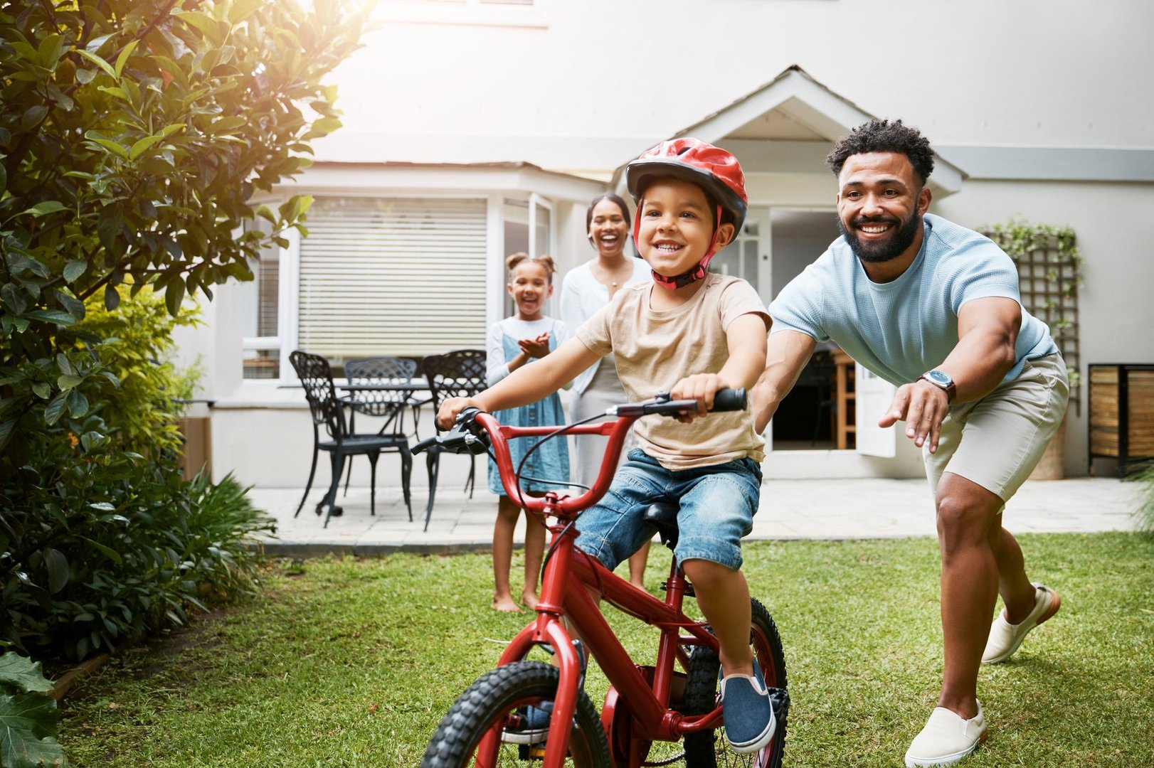 Father teaching son to ride bike in family home backyard