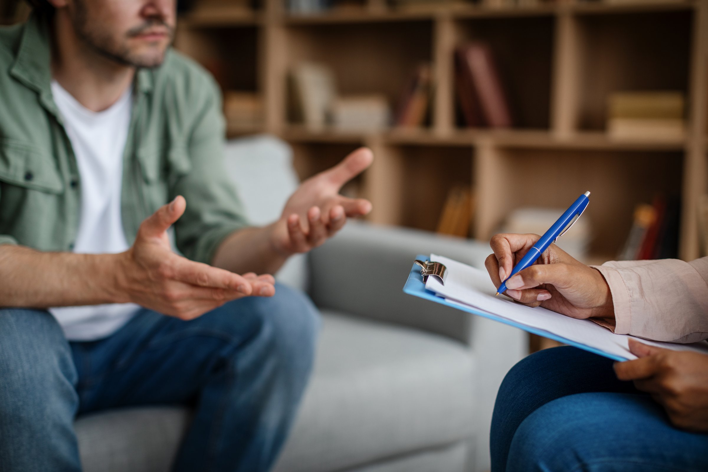 Young african american woman doctor consulting european sad male patient in clinic interior, cropped, close up. Professional medical care, mental problems, treatment of depression, support and help