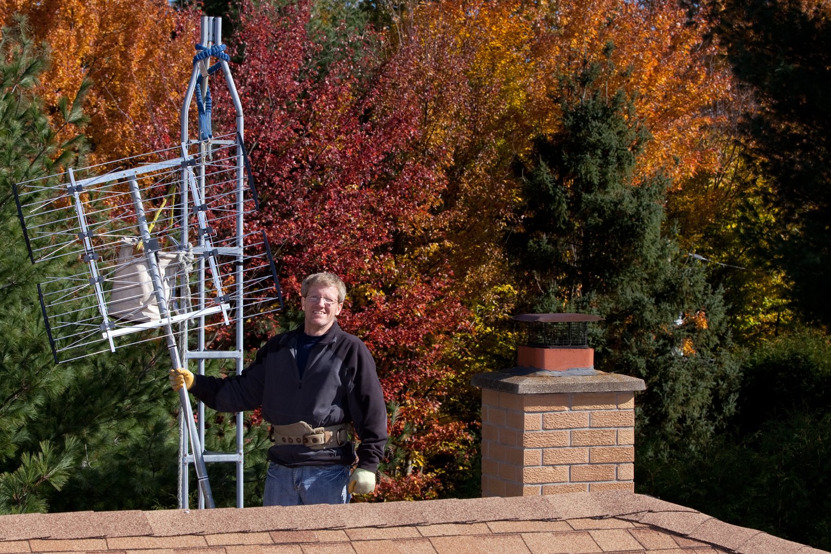 Workman installing HDTV digital antenna on a house