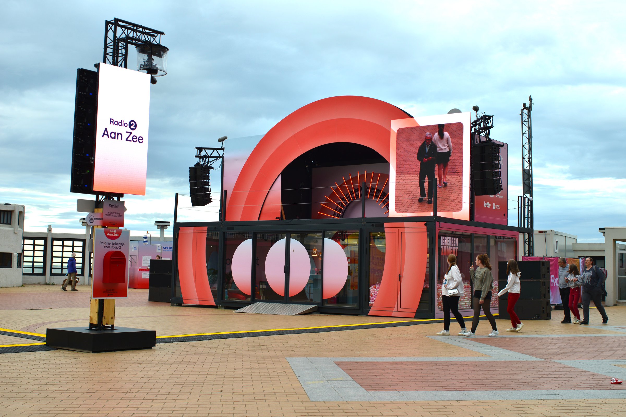 Blankenberge, West-Flanders, Belgium July 6, 2025: Radio 2 aan Zee broadcasting. Teen girls watching to the big media screen outdoor beach promenade