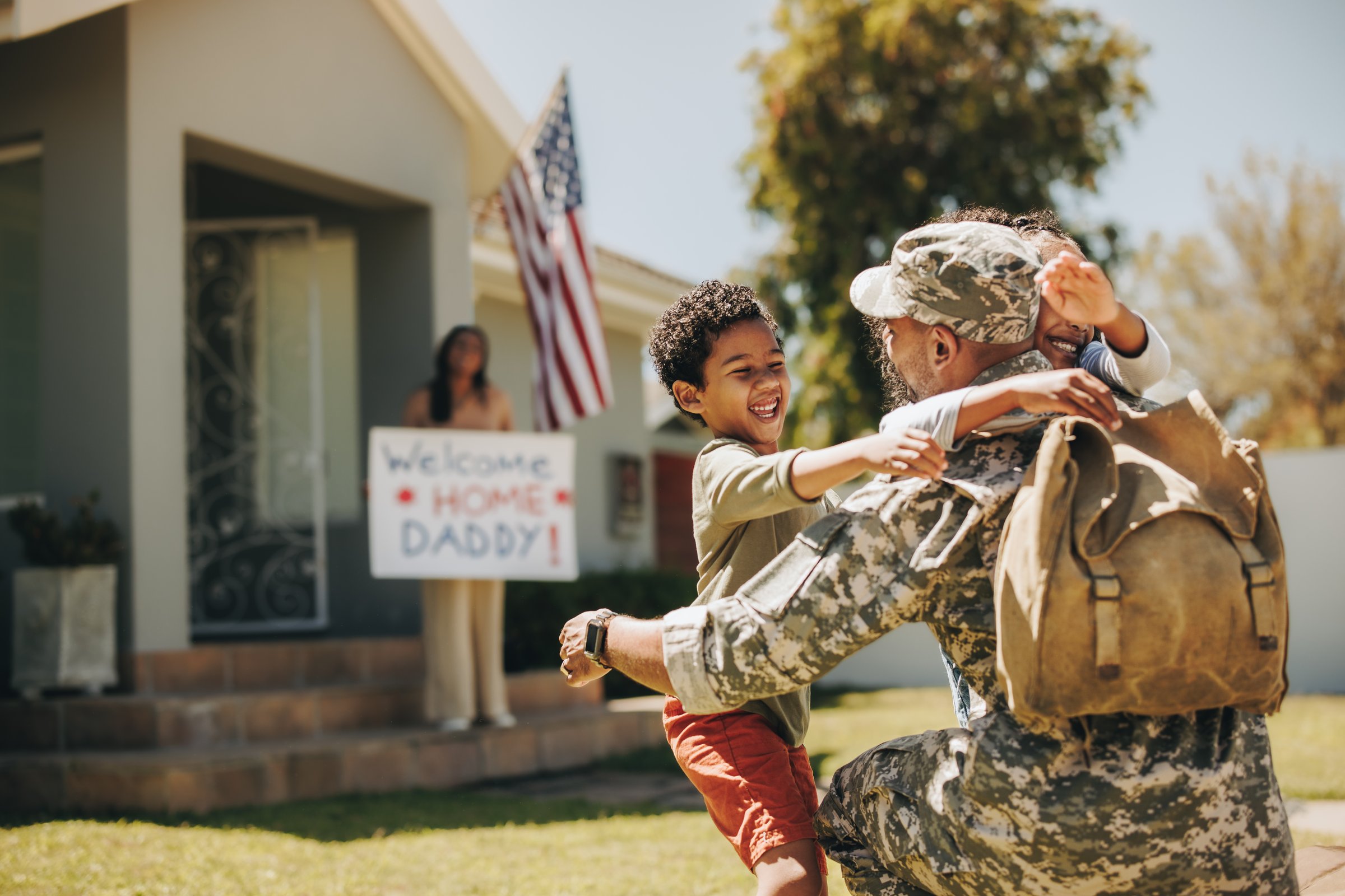 Military dad reuniting with his family at home. American soldier embracing his children after coming back home from the army. Serviceman receiving a warm welcome from his family.