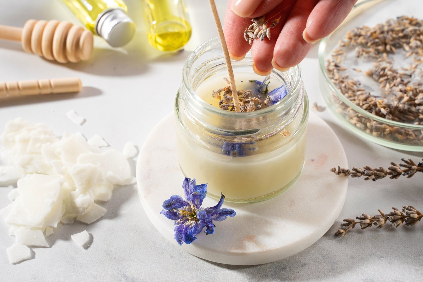 Set tools for homemade natural eco-friendly soy wax candles, wick, perfume, essential oil on a marble table. Making process. Trendy DIY. Craft hobby, small business, artisan products concept.