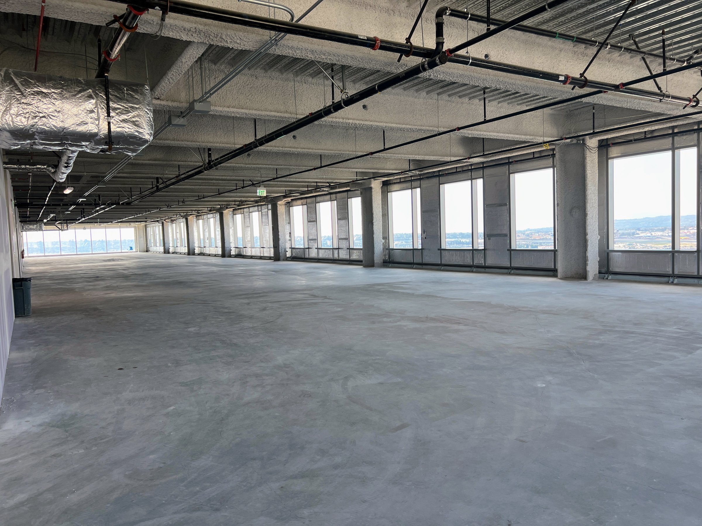 Views of large empty office space in shell condition with exposed beams and concrete