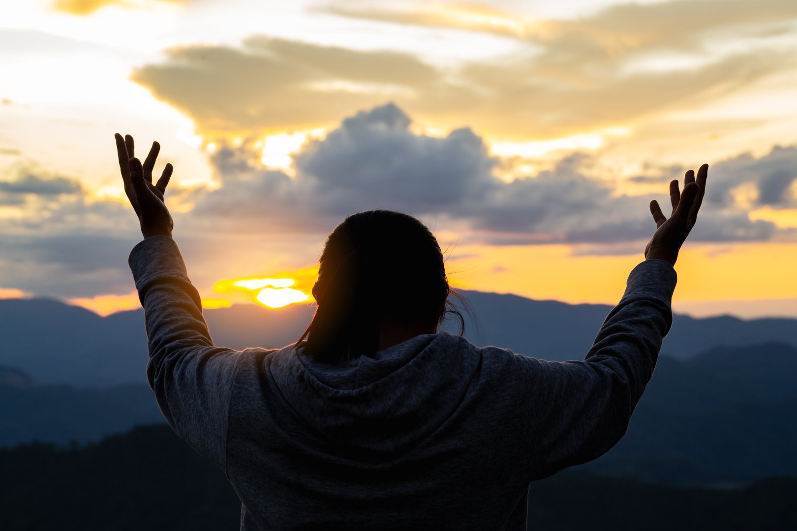Christian woman praying with hands on Bible