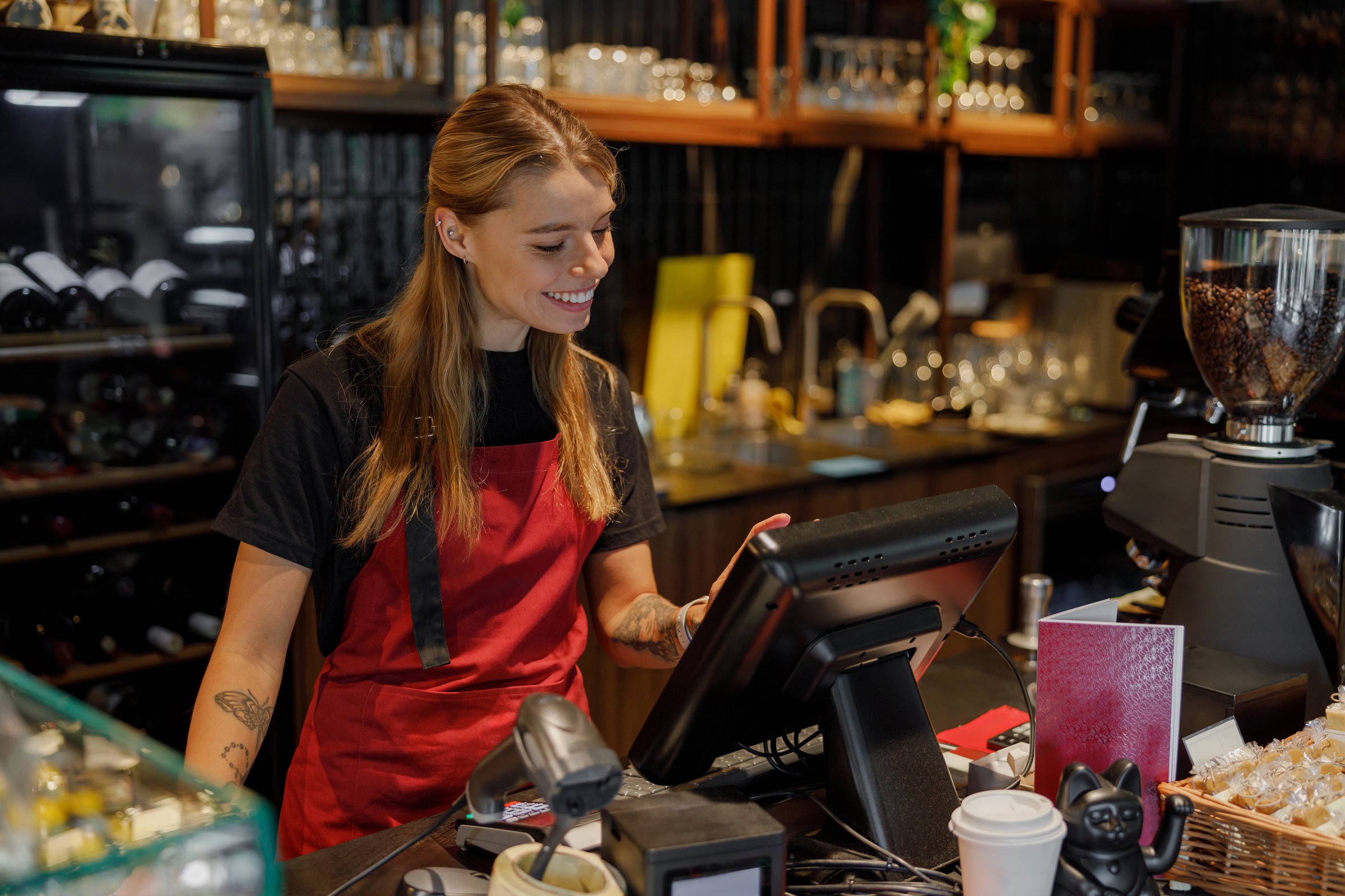 A cheerful barista skillfully using a modern pointofsale system in a bustling coffee shop environment