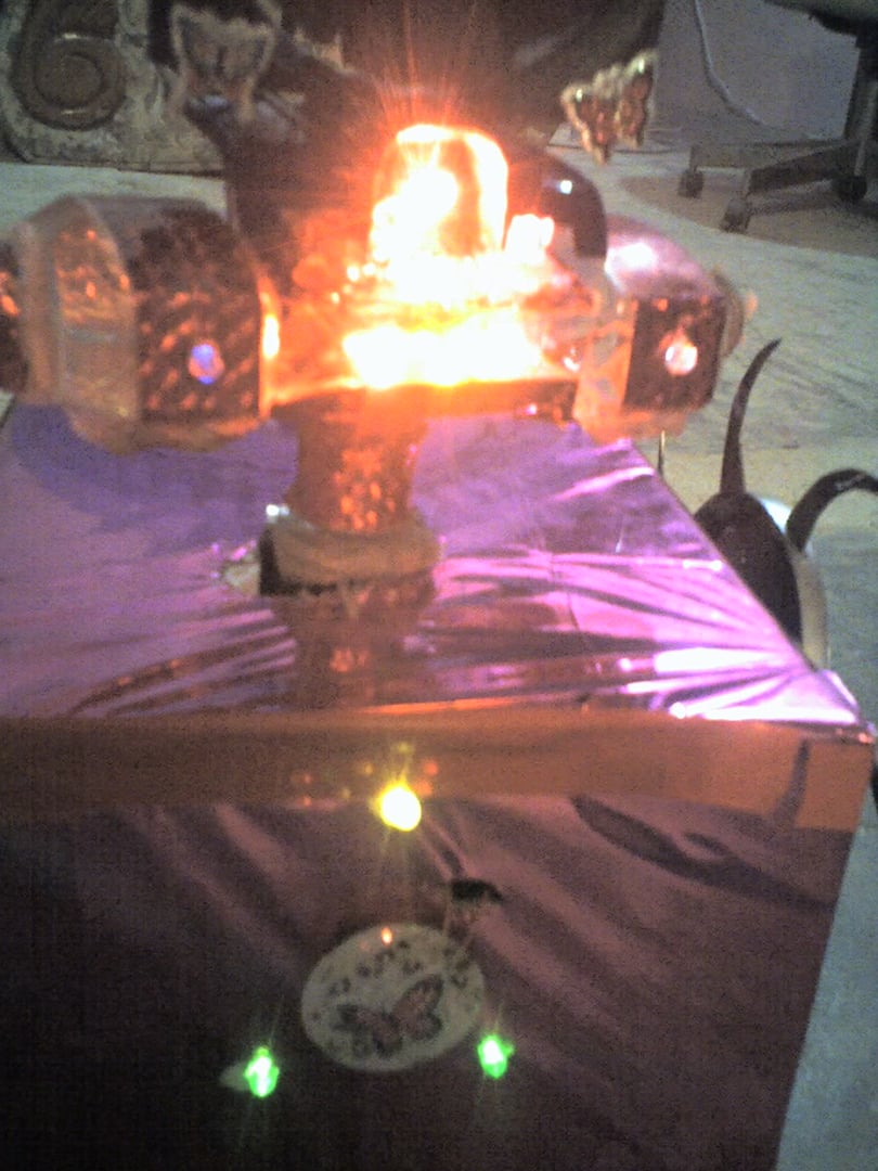 Decorative object with glowing lights and a butterfly motif on a reflective surface, emitting a red-orange light.