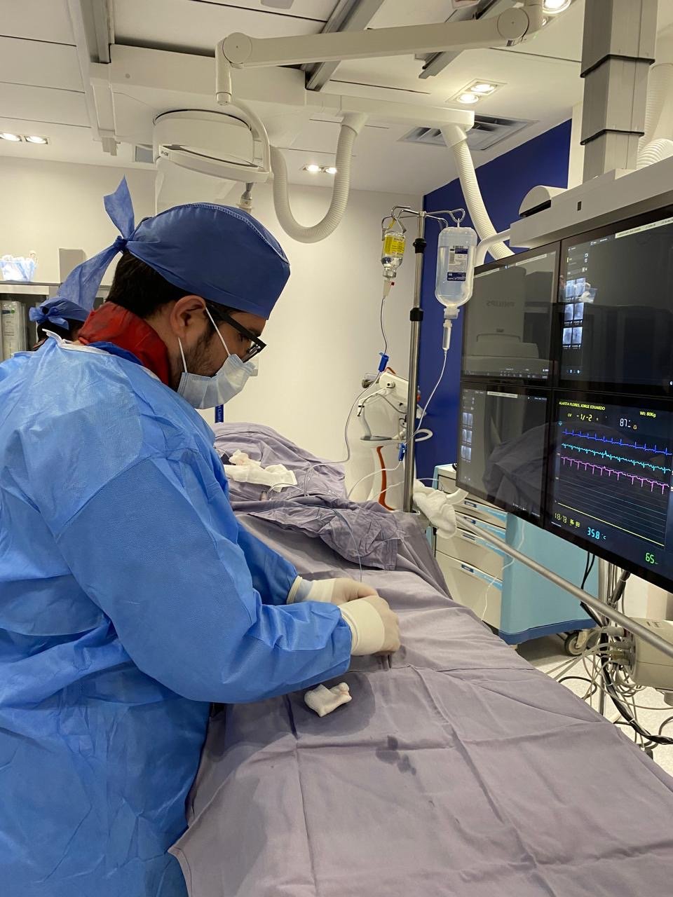 Smiling professional male doctor holding clipboard talking to female patient while sitting at desk in hospital