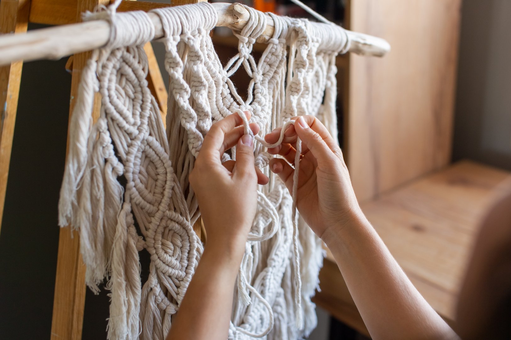 Close-up view of skilled hands intricately weaving a beautiful macrame wall decoration, showcasing craftsmanship and creativity