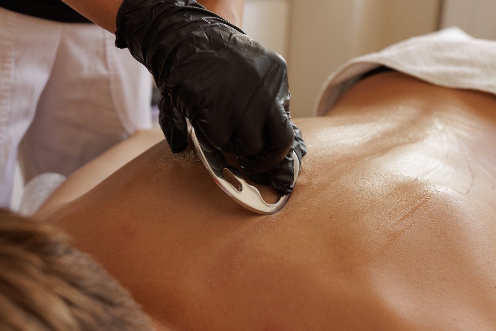 Professional therapist uses a metal scraper for myofascial release and soft tissue recovery in a clinical setting