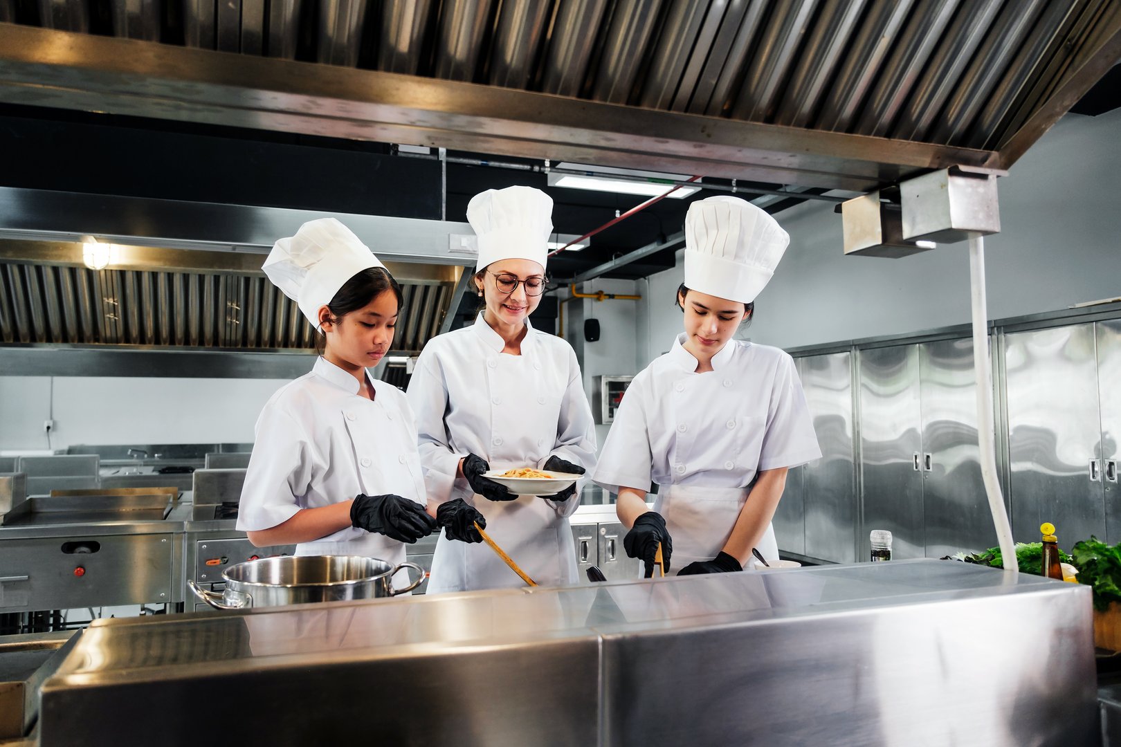 Three professional chefs collaborating in commercial kitchen