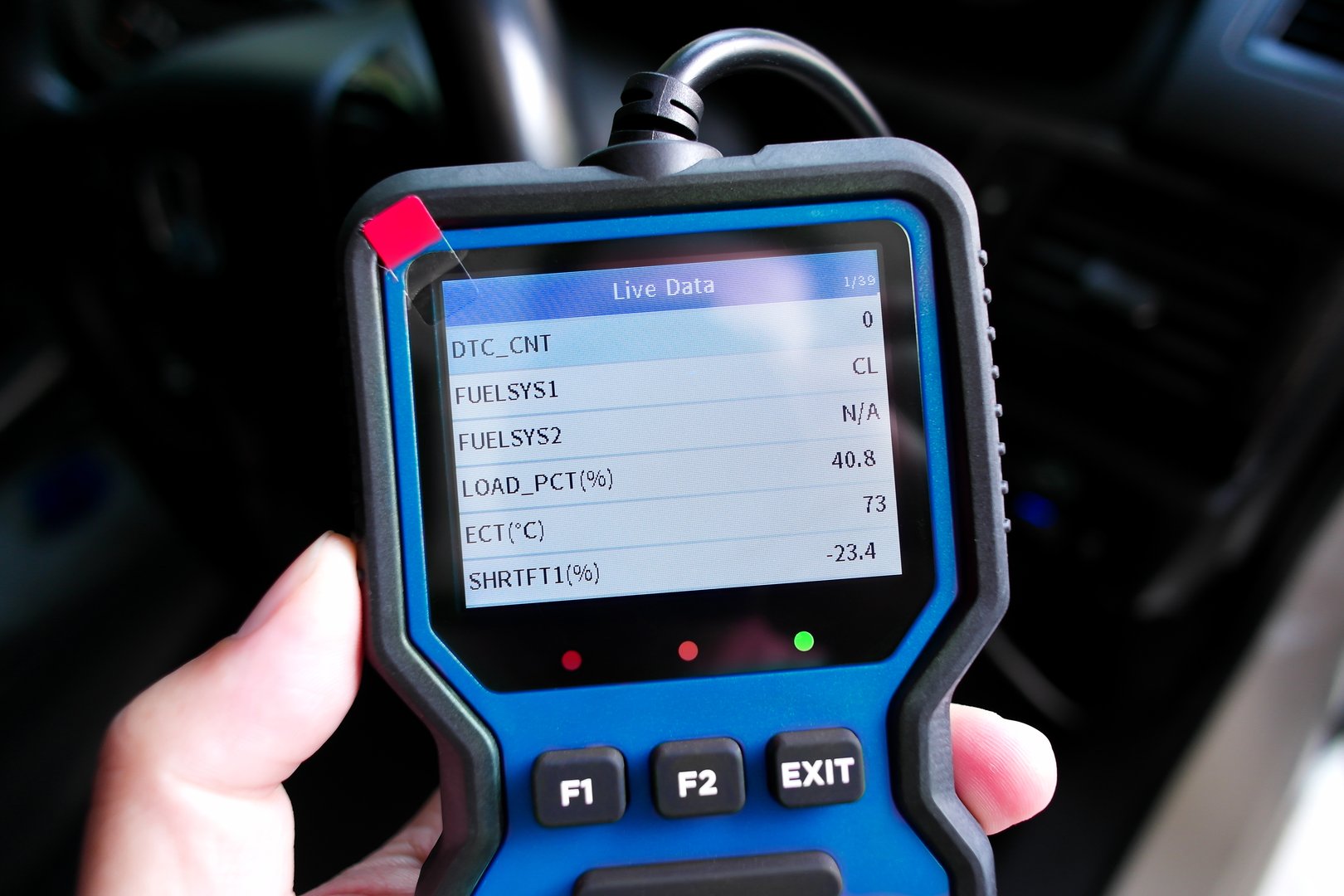Handheld OBD2 scanner showing live engine data with parameters including fuel system status, engine load percentage, coolant temperature, and short-term fuel trim values