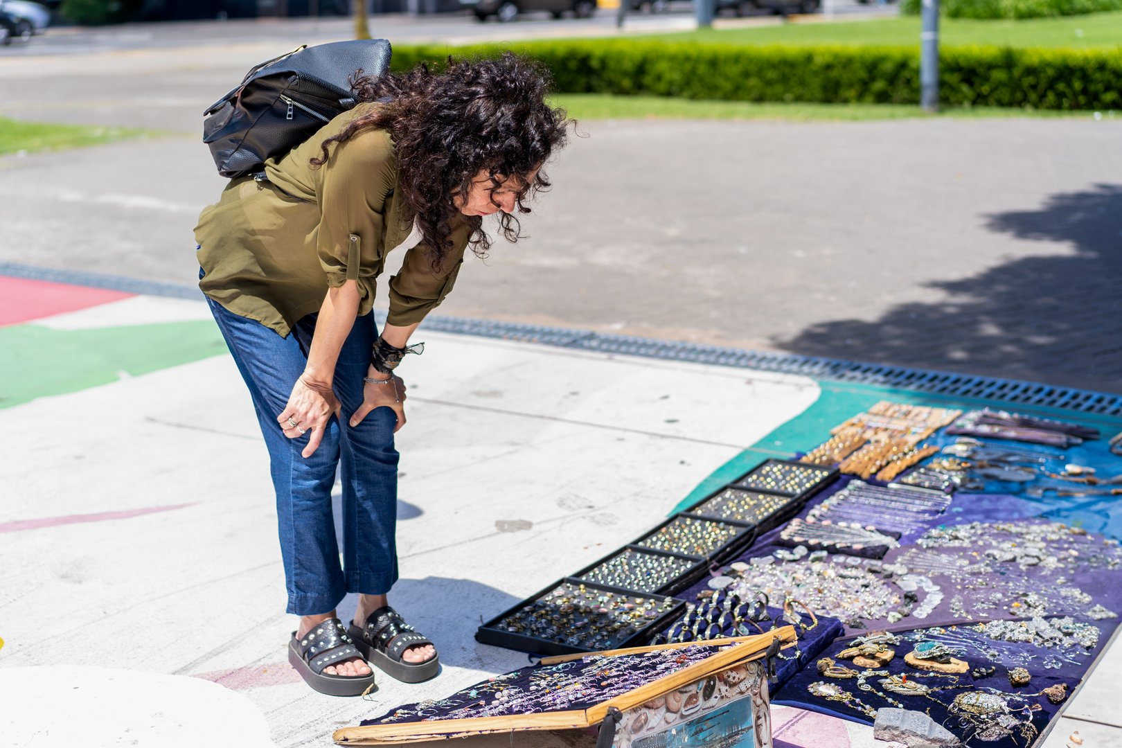 Mid-adult woman browsing handmade jewelry at an outdoor fair