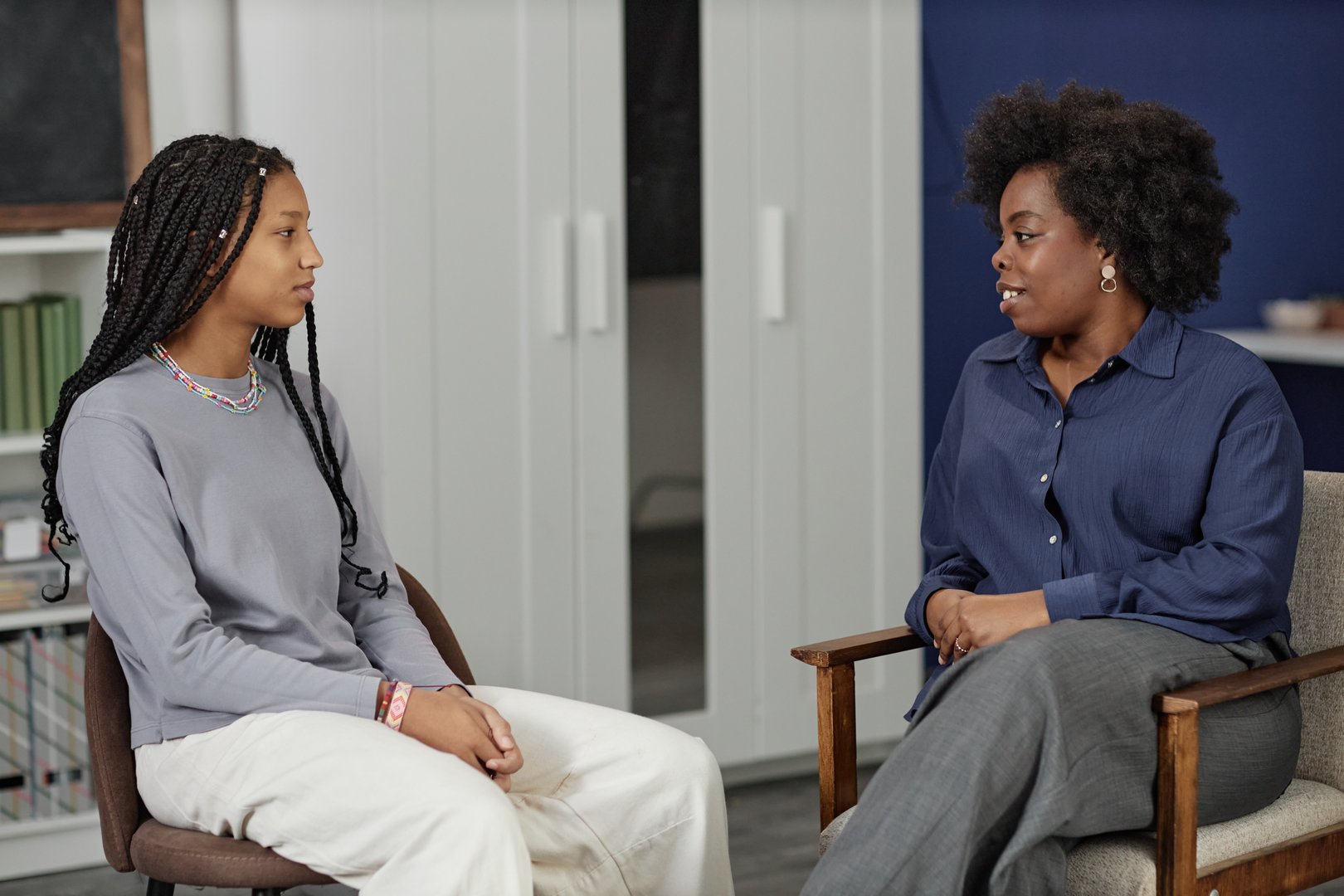 Side view portrait of African American woman talking to teenage girl during therapy session in school or college