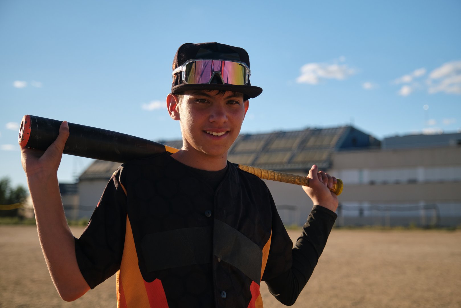 Young man smiling, ready for baseball game, wearing cap and sunglasses