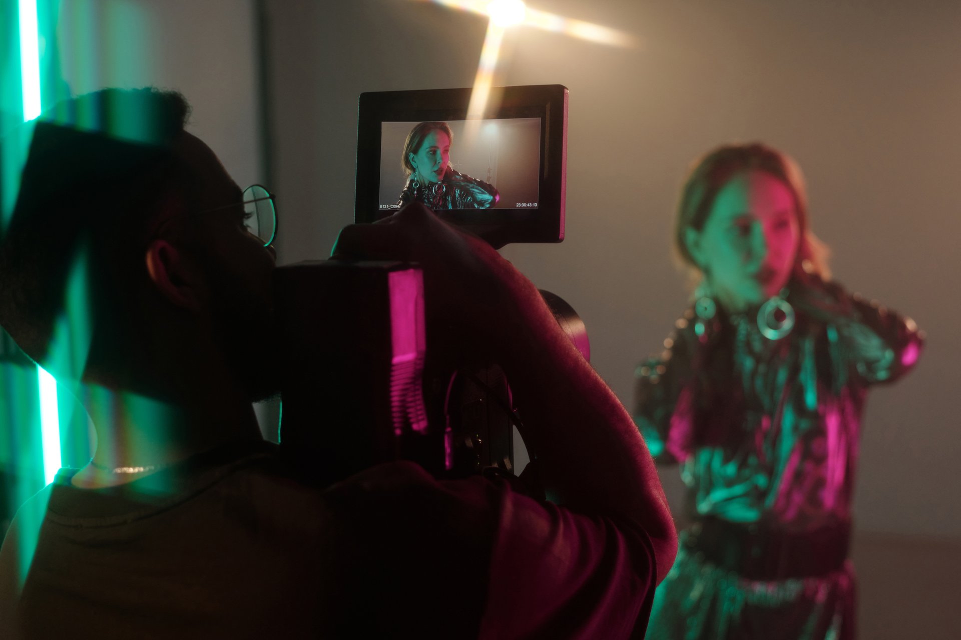 Back view of cameraman holding camera with focus on screen showing actress or musician performing, copy space